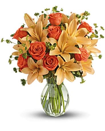 Fiery Lily and Rose - Ignite their heart with this inspirational gift of warm orange roses and lilies. As wondrous as a summer sunset - but quite a bit more fragrant! - it's a versatile choice for men and women alike. Dark orange roses and asiatic lilies are mixed with fresh green bupleurum and variegated pittosporum. Presented in a graceful glass reception vase. Orientation: All-Around