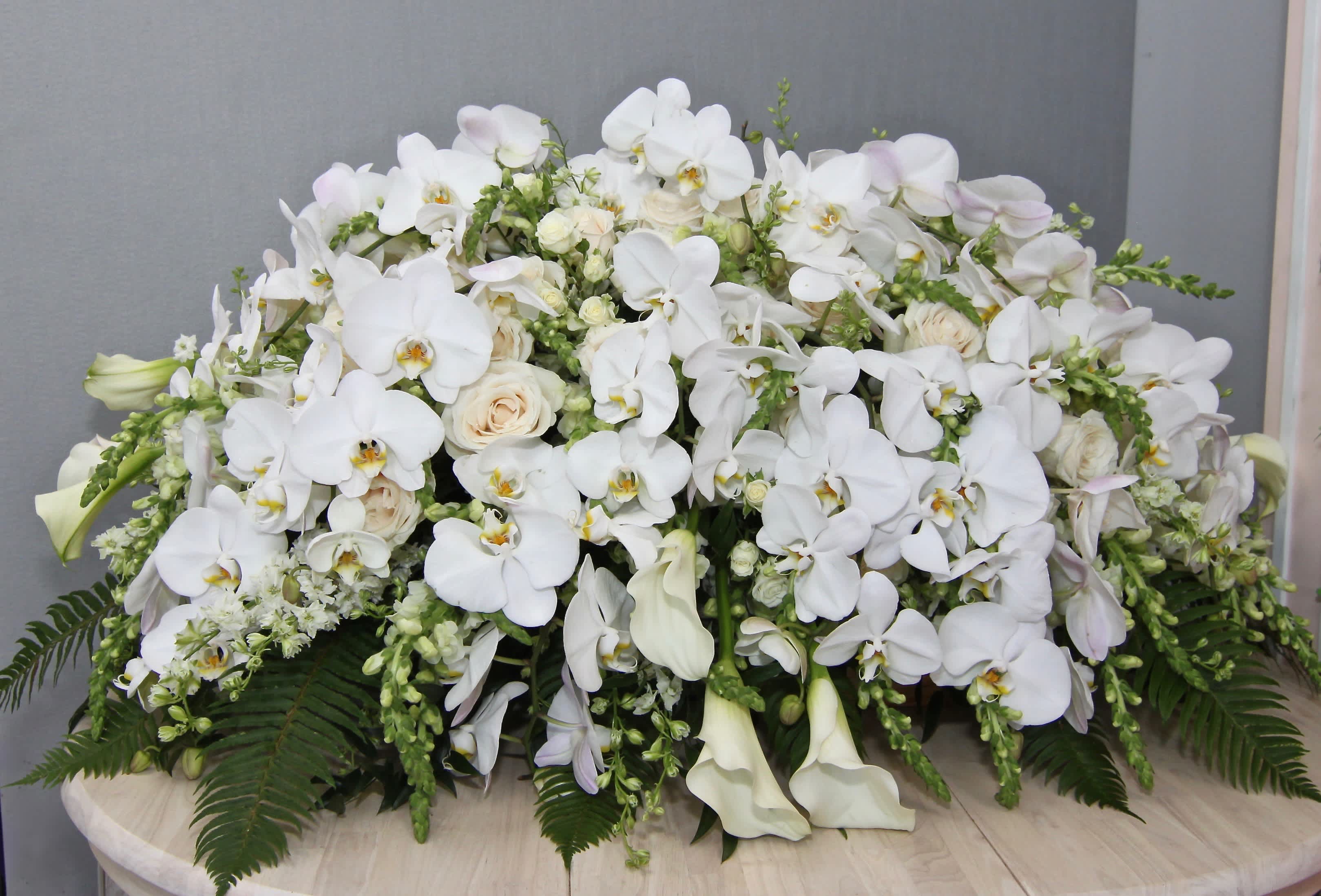 Orchid and Calla Lily Casket Orchid and Calla Lily Casket - This casket arrangement includes white orchids, calla lilies, roses, and snapdragons. Standard size is half casket, deluxe is 3/4 and premium is full casket.