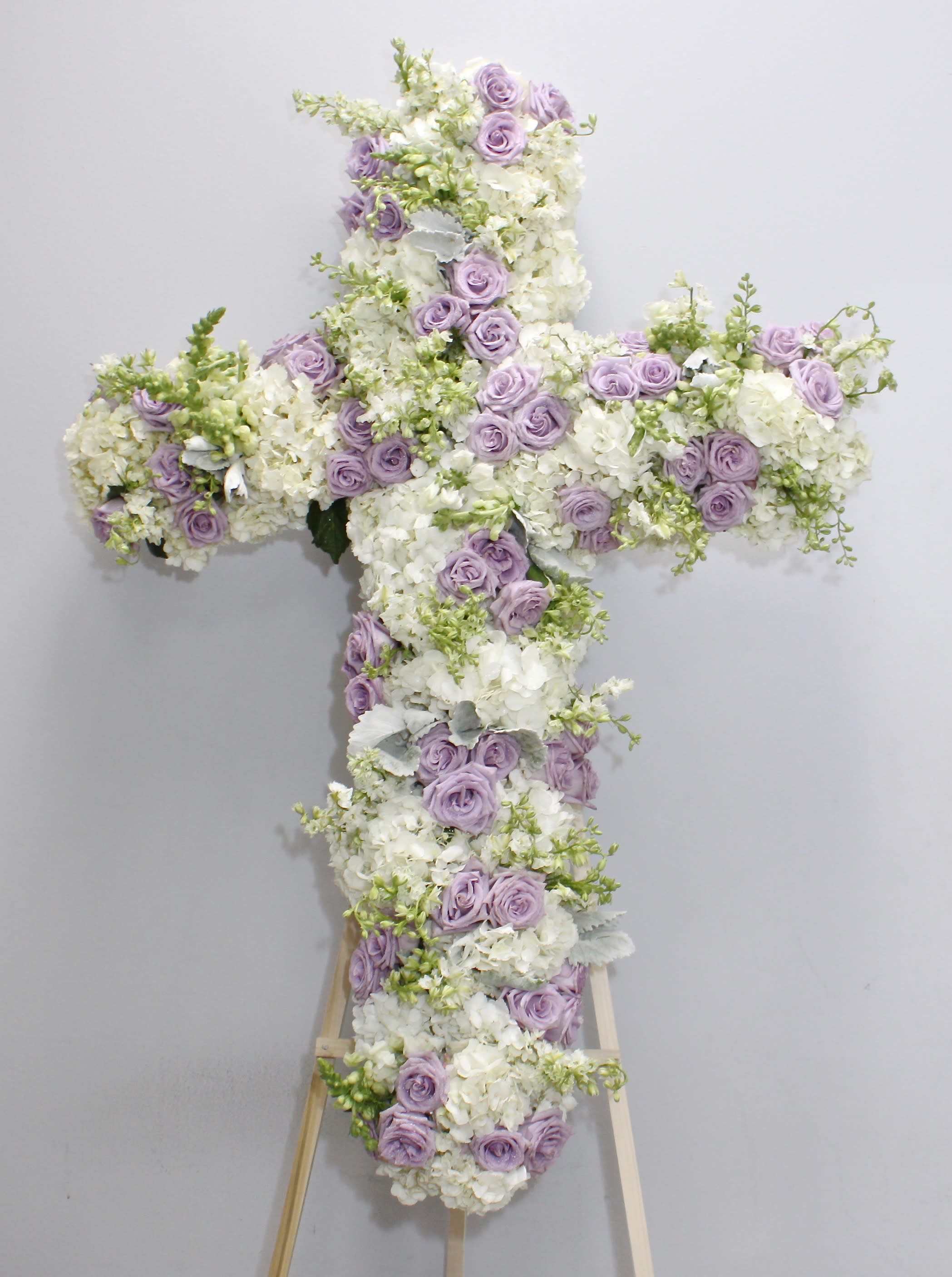 Lavender Rose Cross  - This cross is made a delicate blend of lavender roses, hydrangeas and seasonal greens.    We include easel, printed banner and delivery (some fees may apply). An additional banner can be added for $15.    Standard size is 30'', deluxe is 36'', and premium is 42''.