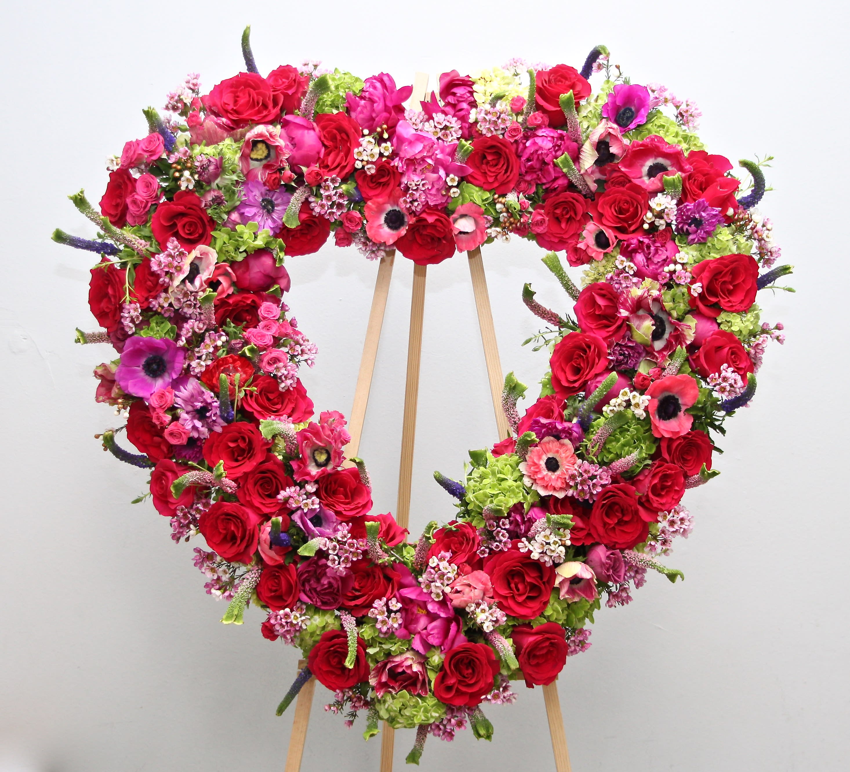 Bright Pinks Heart  - This heart includes bright pink roses, hydrangeas, and seasonal greens.     We include easel, printed banner and delivery (some fees may apply). An additional banner can be added for $15    Standard size is 30'', deluxe is 36'', and premium is 42''.