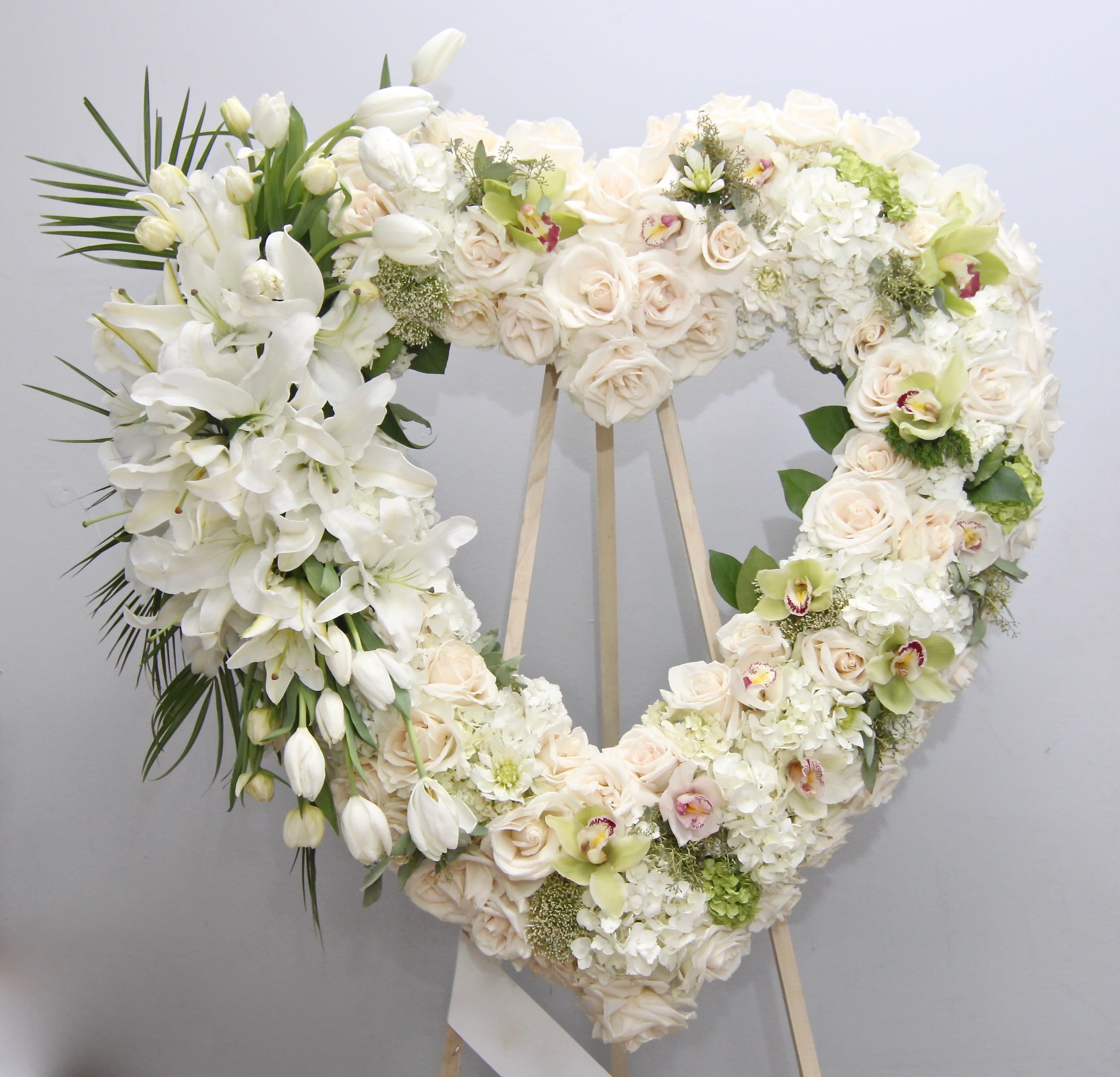 Tulips and Orchids Heart  - Arranged on a base of roses and hydrangeas, this heart also contains orchids, stargazer lilies, tulips, and seasonal greens.    We include easel, printed banner and delivery (some fees may apply). An additional banner can be added for $15    Standard size is 30'', deluxe is 36'', and premium is 42''.