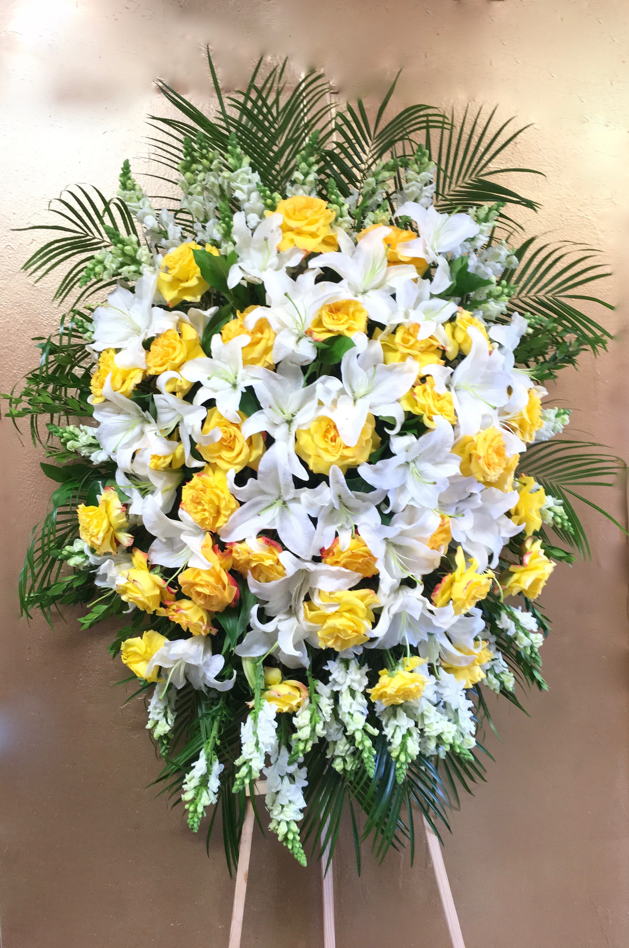 Sunshine Spray  - This sympathy spray includes bright yellow roses, stargazer lilies, and seasonal greens.     We include easel, printed banner and delivery (some fees may apply). An additional banner can be added for $15.    Standard size is 30'' wide, deluxe is 36'', and premium is 42''.
