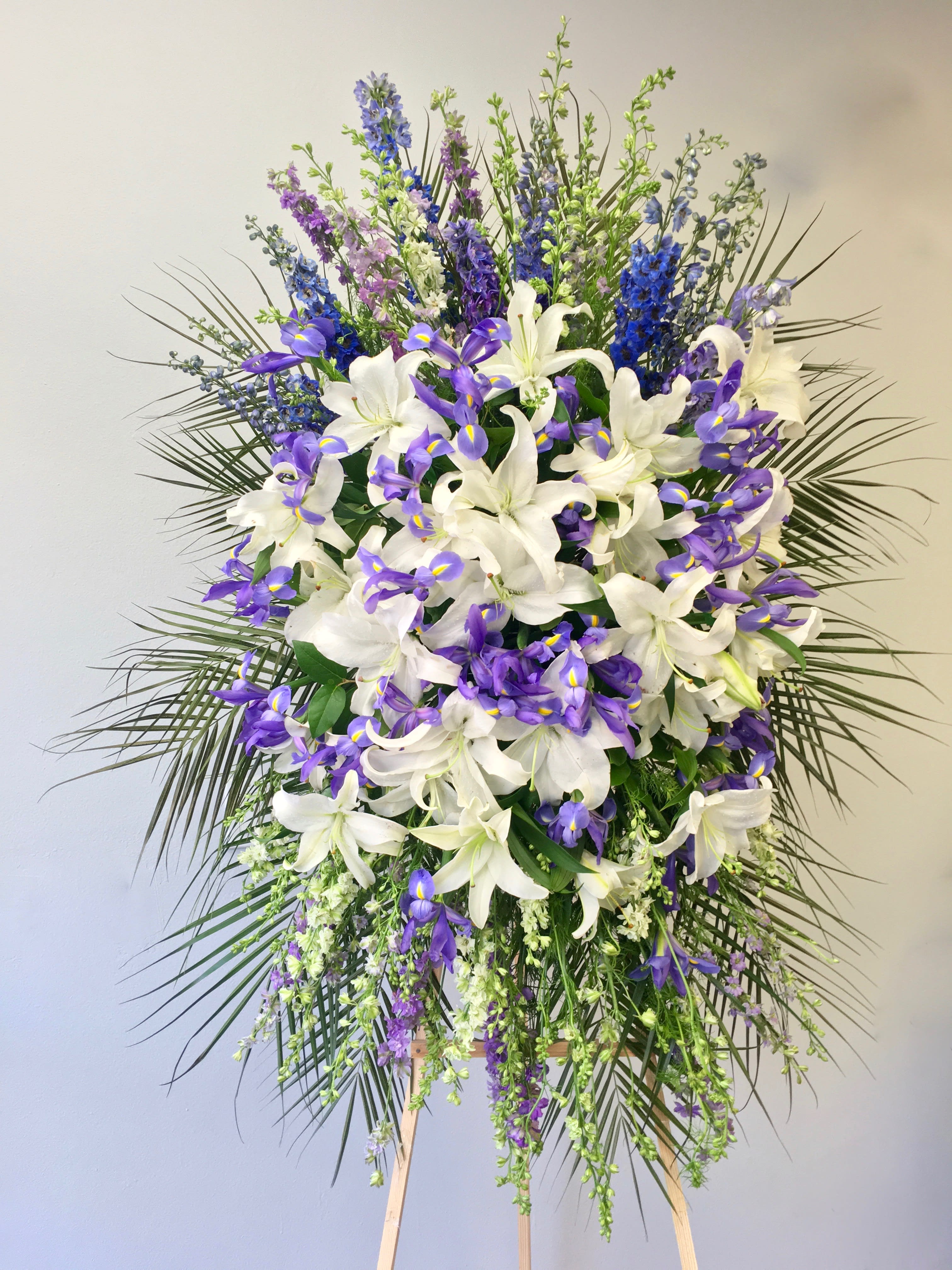 Lavender Iris Spray  - This spray includes a mix of lavender and purple florals, as well as bright white stargazer lilies.     We include easel, printed banner and delivery (some fees may apply).    Standard size is 30'' wide, deluxe is 36'', and premium is 42''.