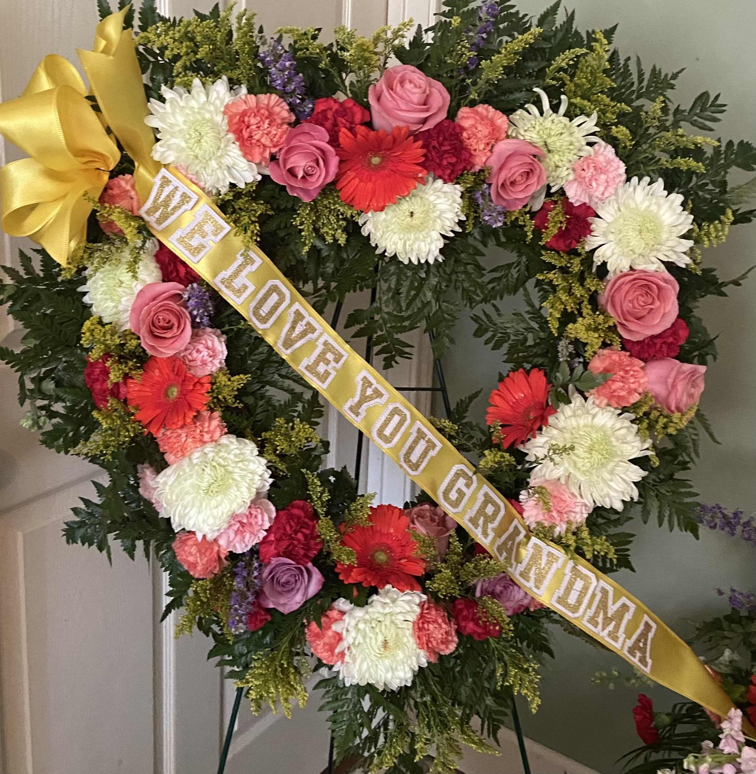Bountiful Garden Heart Spray - Pink roses, lavender roses, pink carnations, peach carnations, orange gerber daisies, solidago, white cremones, purple chaste, pink and white stock, white larksper and red carnations.