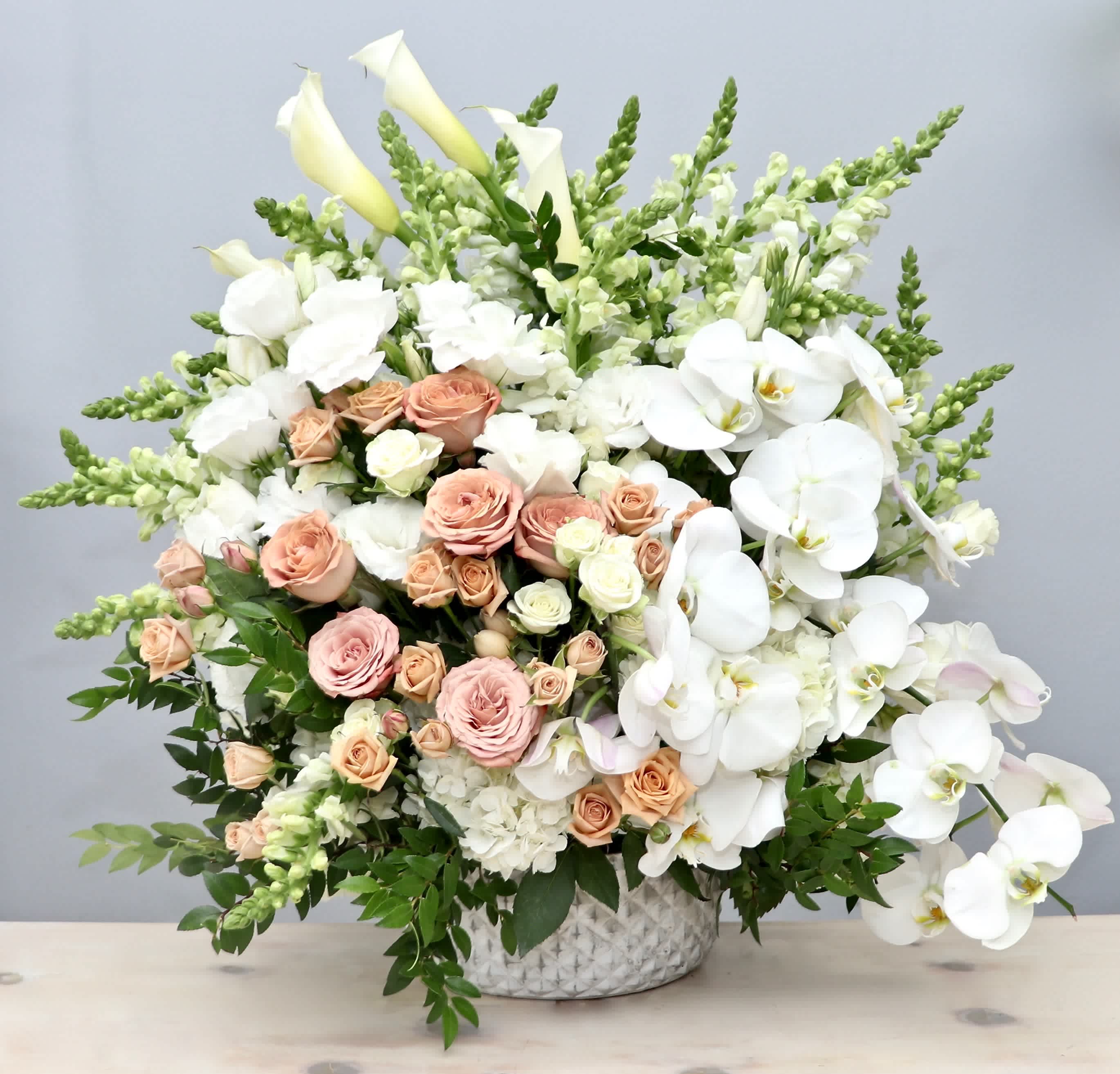 Orchid and Roses Basket Spray - This large arrangement contains a collection of premium flowers, including roses, orchids, calla lilies and snap dragons. 