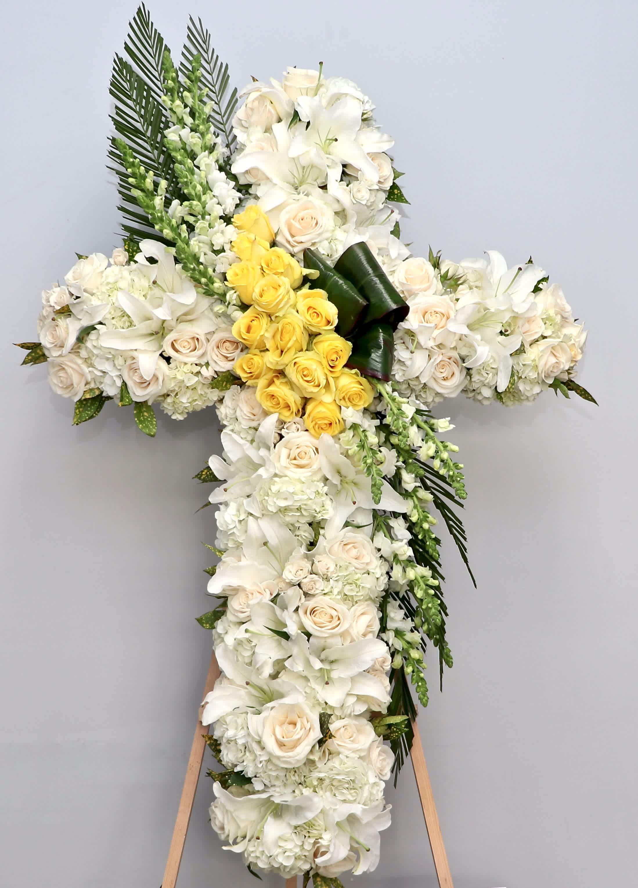 Heart of Gold Cross  - This sympathy cross includes a center of yellow roses, hydrangeas, lilies, and seasonal greens.     We include easel, printed banner and delivery (some fees may apply).    Standard size is 30'', deluxe is 36'', and premium is 42''.  