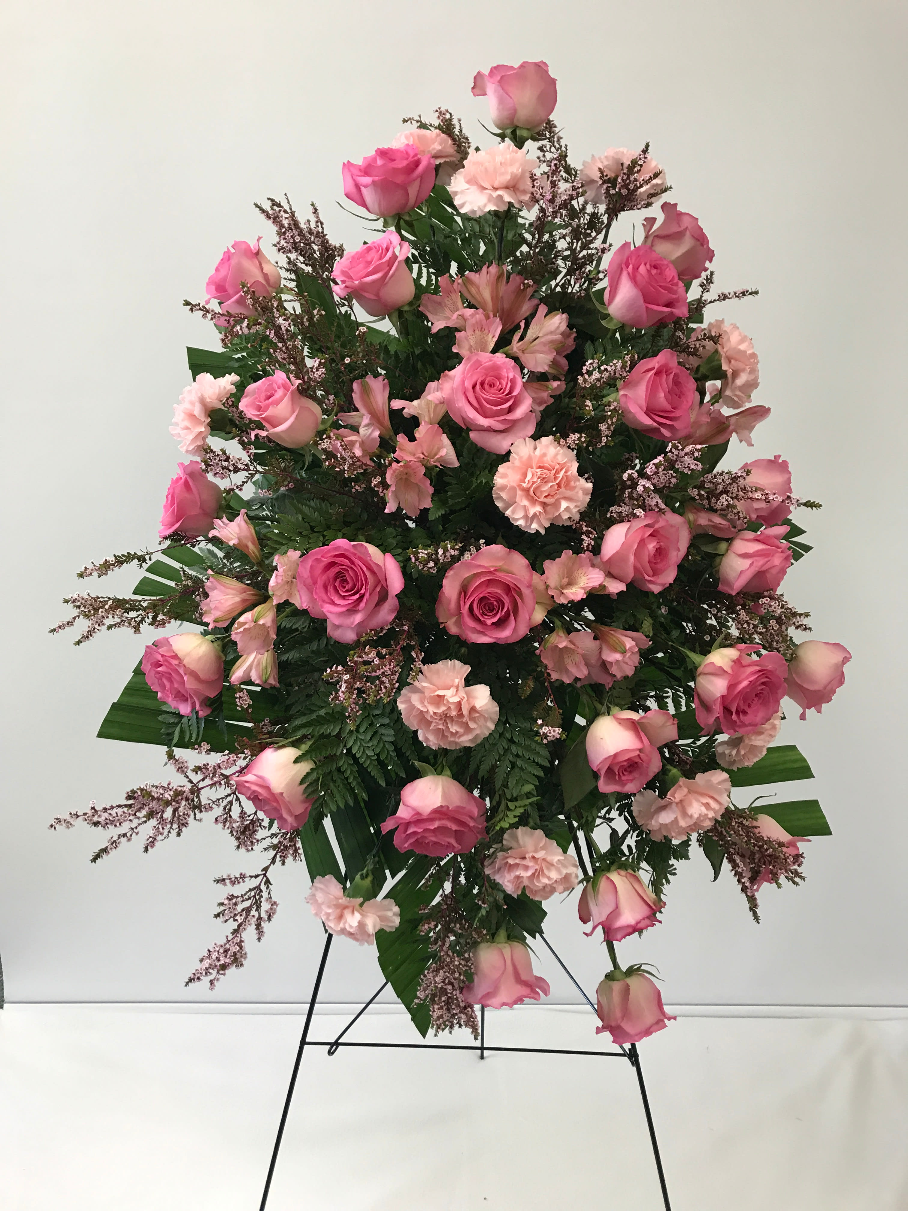  Pink Tribute Spray - With a bounty of lovely pink flowers and simple greens, this pretty spray lets you express your sympathy beautifully.  Splendid pink, hot pink and light pink flowers such as roses, alstroemeria, carnations, and more create a display that is warm and loving.      Orientation: One-Sided       