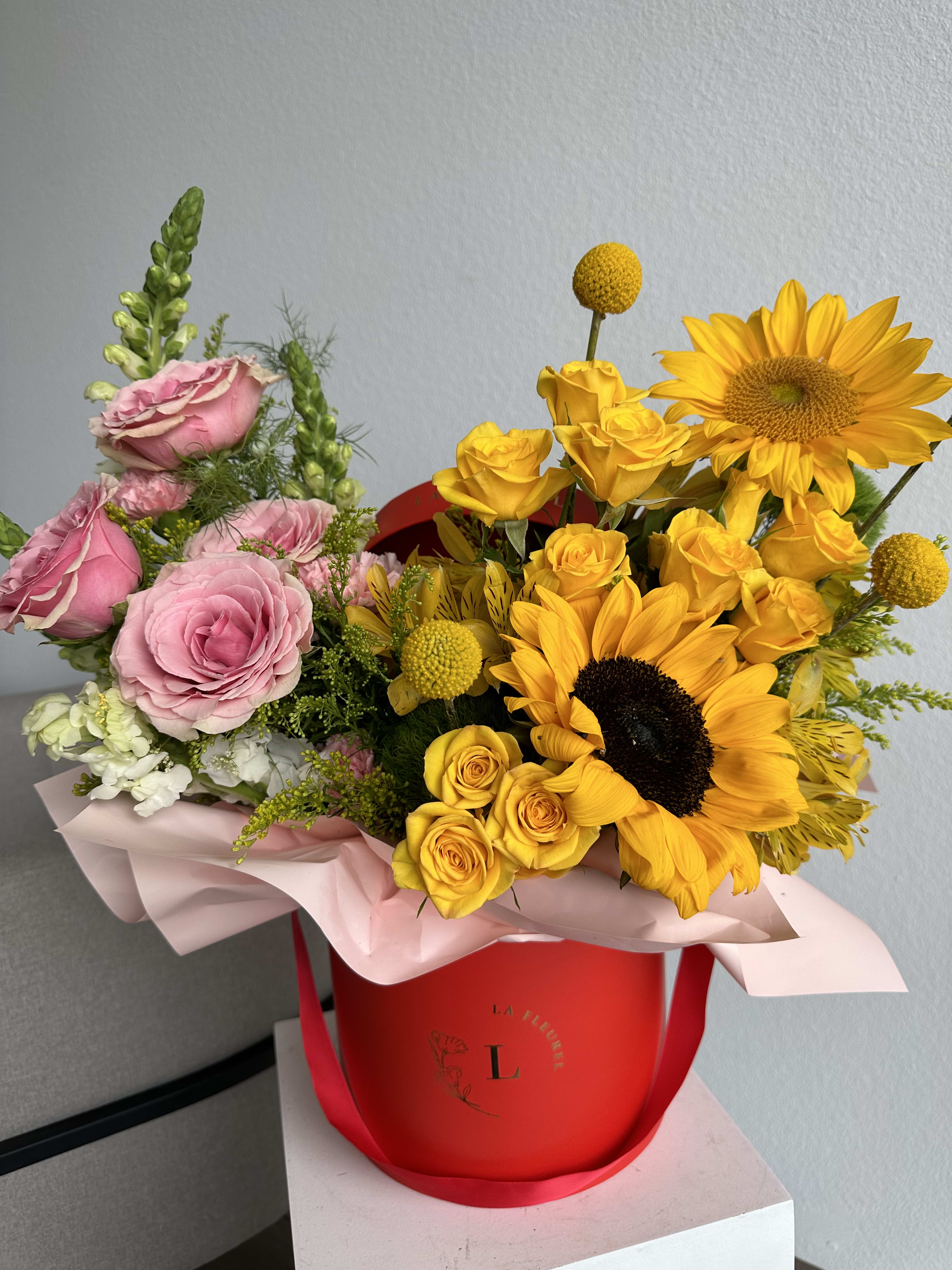 Sunflower Whispers - This beautiful arrangement is filled with yellow and pink roses, hydrangeas, sunflowers and greens to deliver your special message to your special someone.  Perfect for any occasion. You can choose any color of the box.  Arrangement includes: Flowers SMALL BOX Custom greeting card