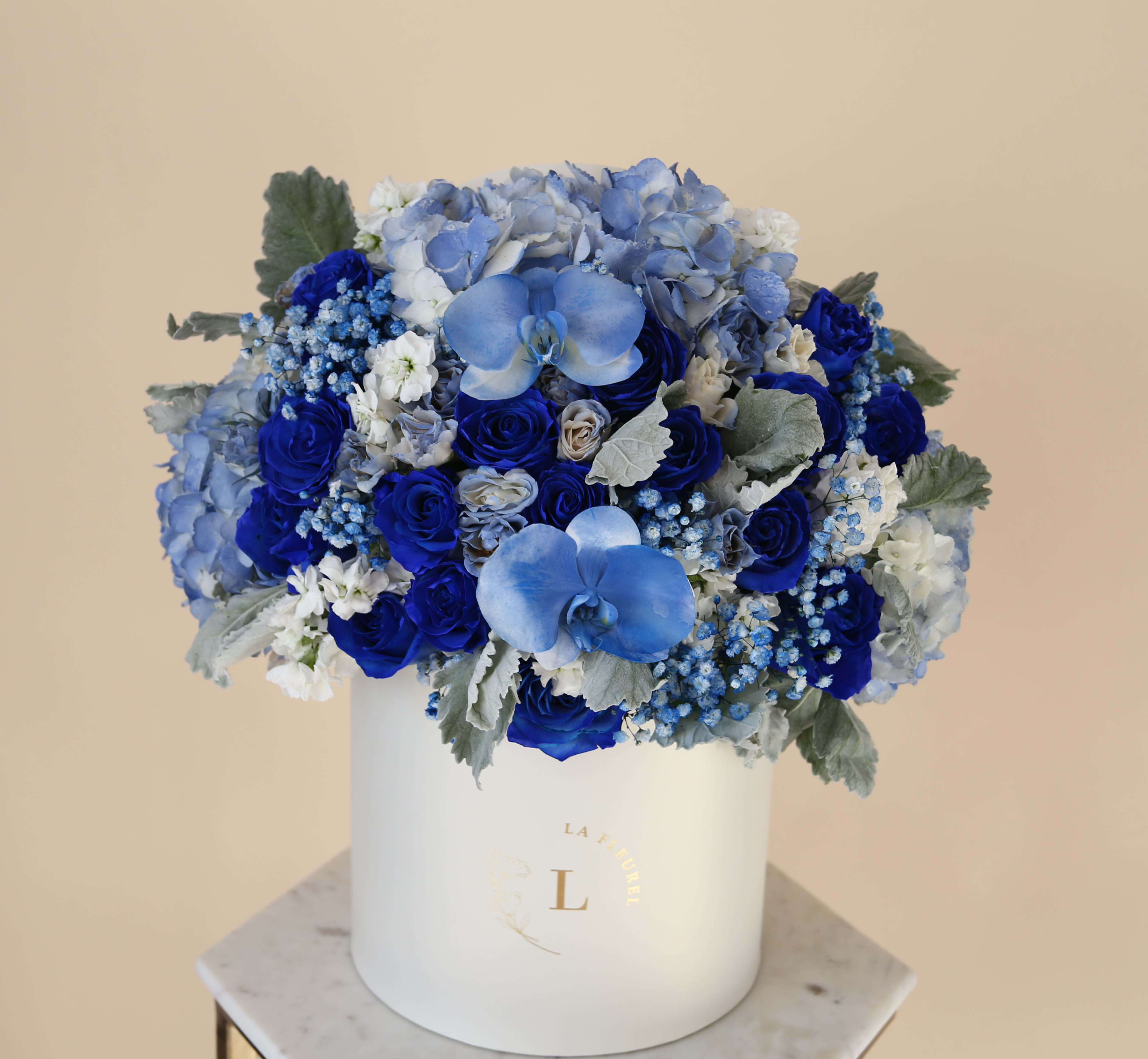 Blue Charm Arrangement - This gorgeous arrangement filled with the royal blue roses,hydrangeas, greens and orchids to deliver your special message to your special someone. Perfect for any occasion.   Arrangement includes: Fresh blue roses, blue hydrangeas, greens and orchids.  Medium box measured at 9.75&quot; Dia. x 9.25&quot; H Custom greeting card
