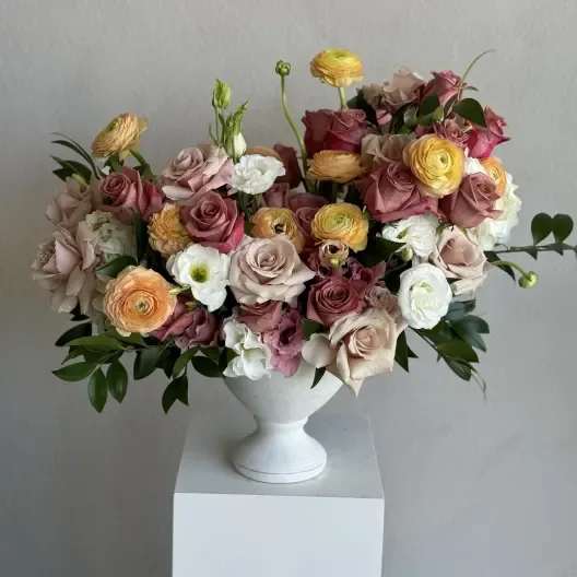 Barista Roses - A charming arrangement of warm-toned roses that evoke the richness of a perfectly brewed coffee and latte, yellow ranunculuses, greens and all beautifully presented in a sleek white ceramic vase. This bouquet blends warmth and sophistication, ideal for adding a cozy yet refined touch to any setting.