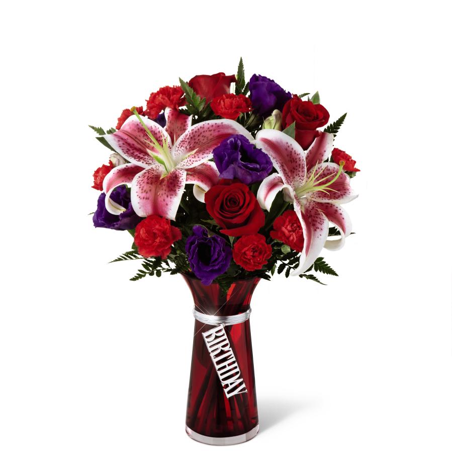 Birthday Wishes Bouquet - The Birthday Wishes Bouquet is bursting with blooming color and beauty to celebrate your special recipient's big day! Bold red roses, exquisite pink lilies, red mini carnations and purple alstroemeria are accented with lush greens to create an incredible flower arrangement. Presented in a designer red glass vase with a silver metallic decorative tag stating, Birthday, dangling from the neck, this mixed flower bouquet will make their birthday a day blossoming with happy wishes. 