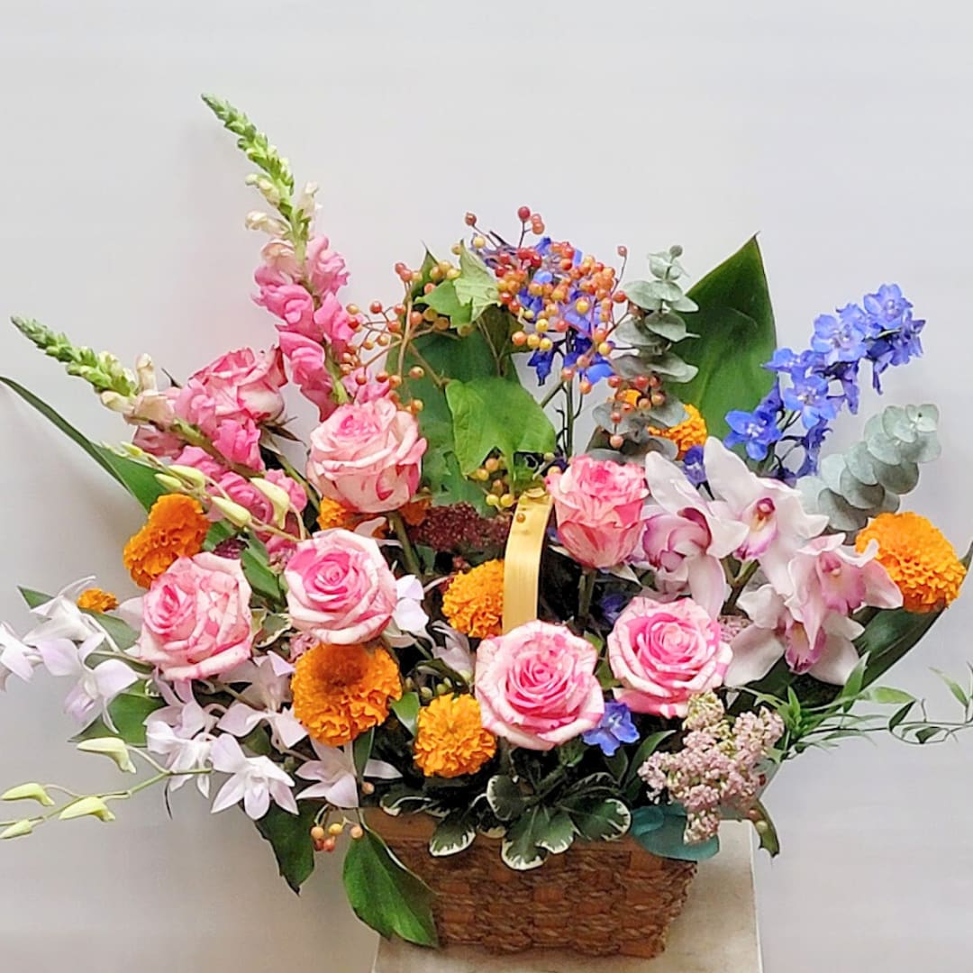 Serendipity Flower Basket - A basket of mixed flower arrangements in beautiful color combinations. Vibrant and energizing, with soft pink tones and touches of blue and orange, it's a great gift for any occasion.