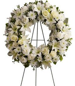 Love Me Tender Wreath - A ring of fragrant, bright white blossoms will create a serene display at any funeral or wake. This classic wreath is delivered on an easel, and is a thoughtful expression of sympathy and admiration.  Arrangement Details:  A standing wreath created from fresh white flowers such as roses, Asiatic lilies, carnations and cushion spray chrysanthemums – accented with greenery – is delivered on an easel.  