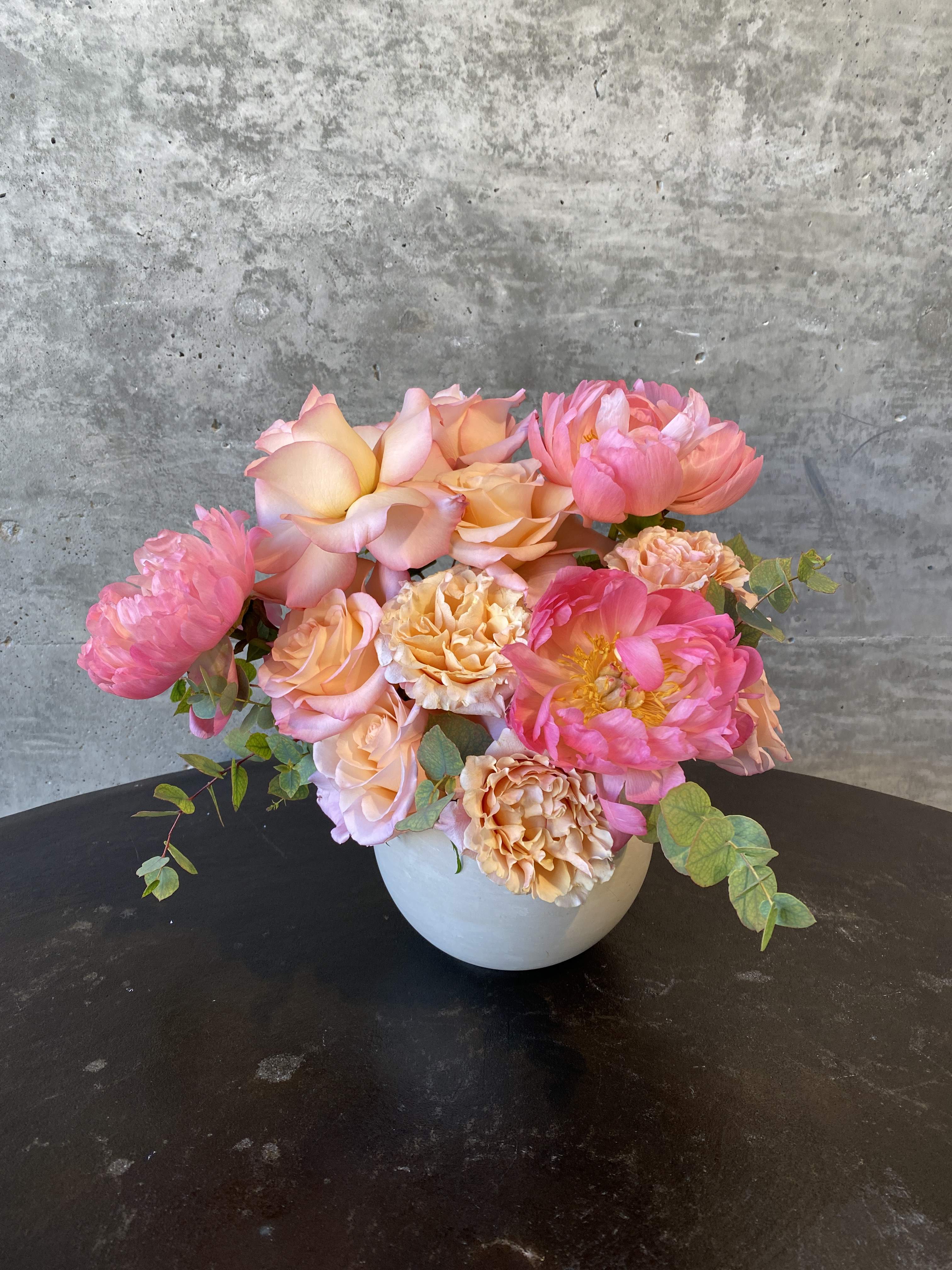 Coral Charm - A moderately sized arrangement with peonies, eucalyptus, and various roses. 