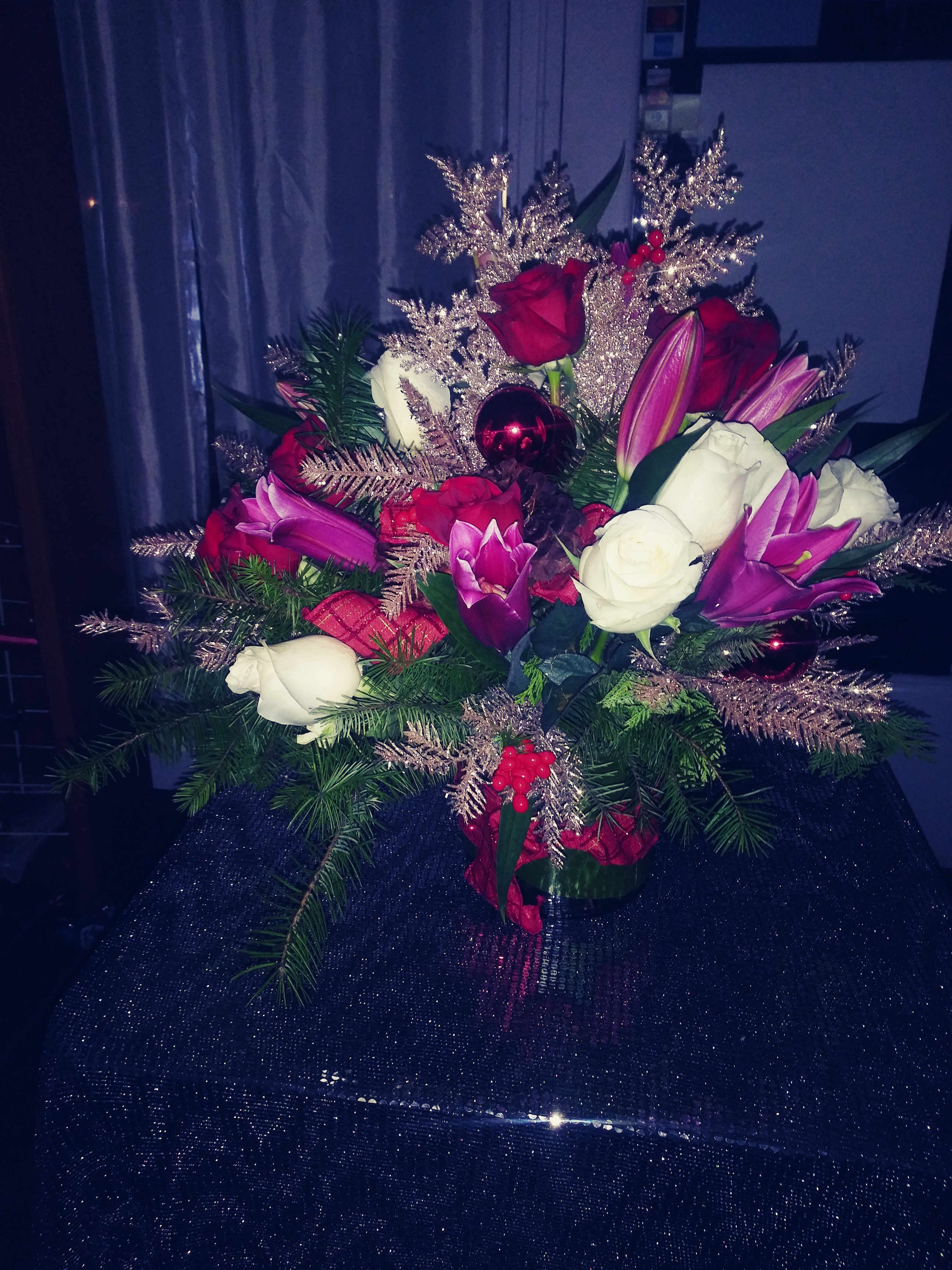 Winter Sparkle Winter Sparkle - This wonderful winter creation is filled with bright pops of pink, red, and white. The hot pink Asiatic Lilies and red roses are complemented by Christmas greenery, red ornaments, berries white roses and sparkle. You can't go wrong with this holiday masterpiece.