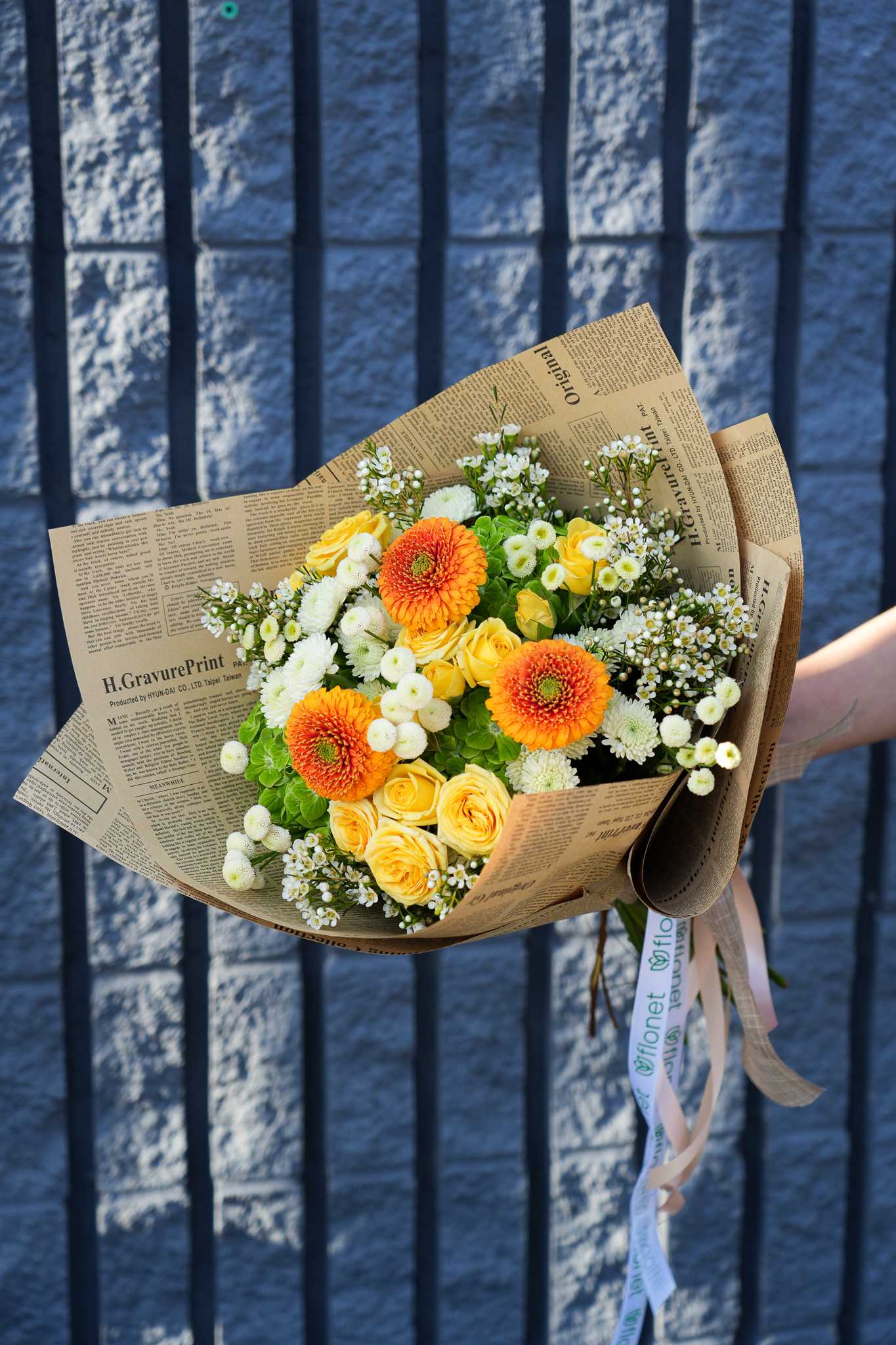 Sunshine Delight Bouquet - Brighten someone's day with the Sunshine Delight Bouquet, a radiant arrangement that captures the warmth and joy of a sunny day. This vibrant bouquet features cheerful yellow roses, striking orange gerbera daisies, and delicate white blooms, all artfully arranged and wrapped in charming newspaper-style paper. Perfect for any occasion, from birthdays to celebrations or just because, the Sunshine Delight Bouquet brings a burst of happiness and positivity to any setting. Let this delightful arrangement be the perfect gesture to convey your heartfelt sentiments.