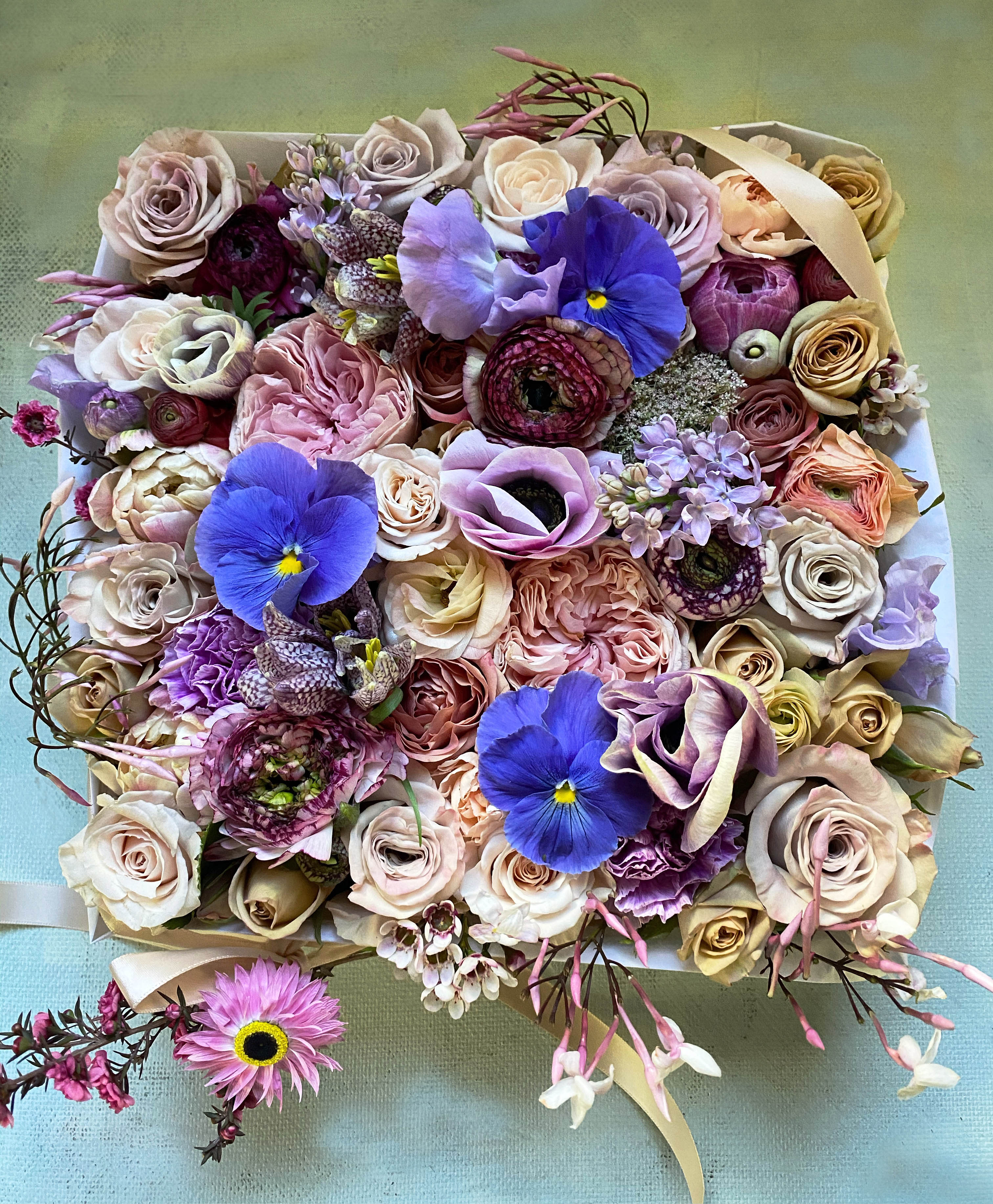 Finley Flower Box - Beautiful flower box suited both for him and her full of fresh seasonal flowers in a blue, nude and pale pastel palette with little hints of lovely garden flowers. Perfect as a gift for that unique person, who needs a flower gift to remember. The box is made in natural light wood, is 8&quot; by 8 inches&quot; and 4&quot; tall. You can upgrade to Deluxe for more luxurious flowers and to premium for a larger box, 14&quot; by 14&quot; filled with the most gorgeous flowers,. We wrap in silk paper and use beautiful ribbon, pretty wrapping details for that beautiful impact at delivery. Blomst LA only uses fresh, high quality flowers, all carefully selected every day to fit your flower order. We offer a personal hand delivery by our own delivery staff and guarantee the flowers will look perfect, when they arrive. We deliver in Glendale, Pasadena, Eagle Rock, Hollywood, Burbank, Beverly Hills and the Pacific Palisades - and everywhere else in Greater Los Angeles. 
