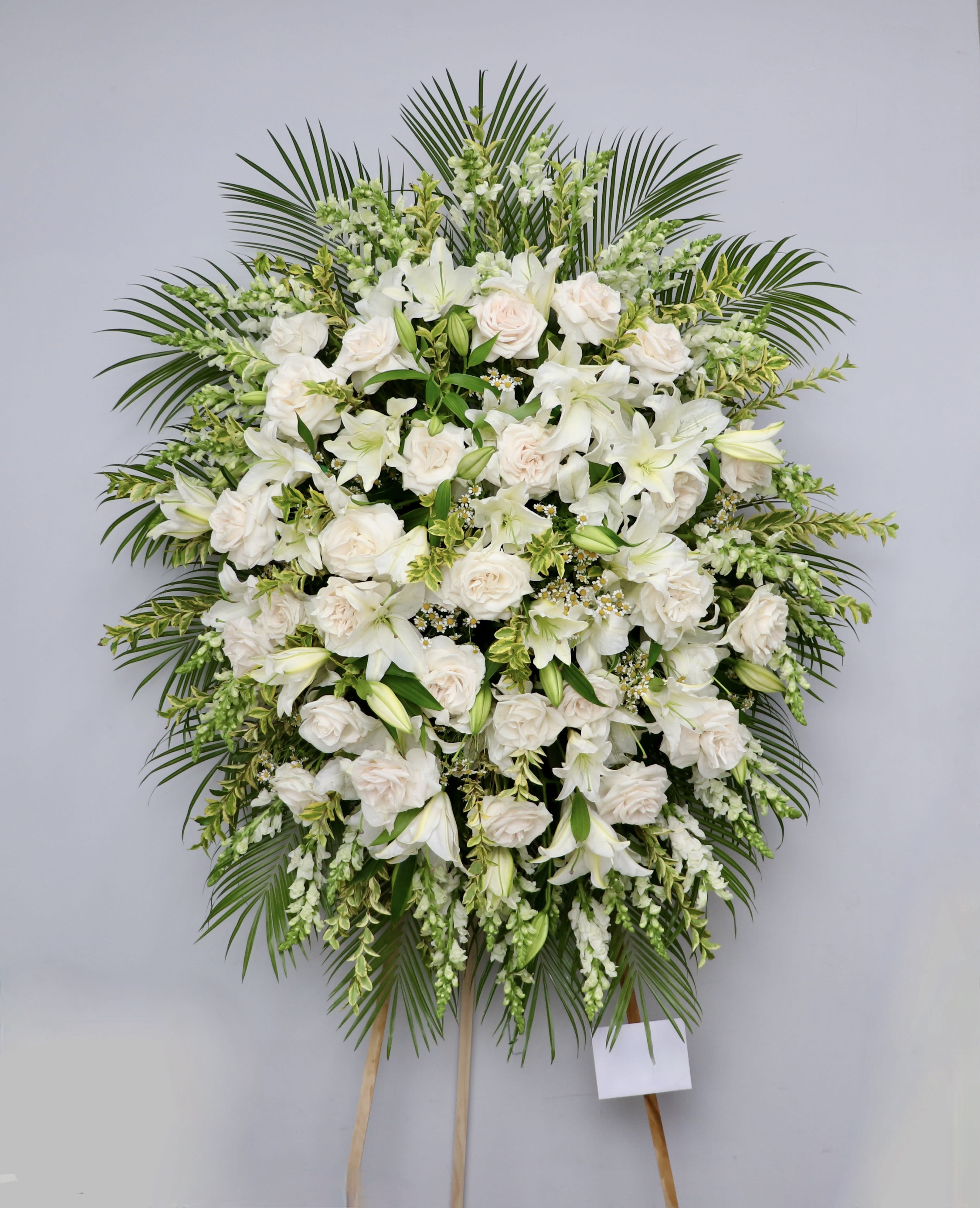 White Rose Remembrance  - White spray filled with lilies, roses, and snapdragons.     We include easel, printed banner, and delivery (some fees may apply). An additional banner can be added for $15.    Standard size is 30'' wide, deluxe is 36'', and premium is 42''.