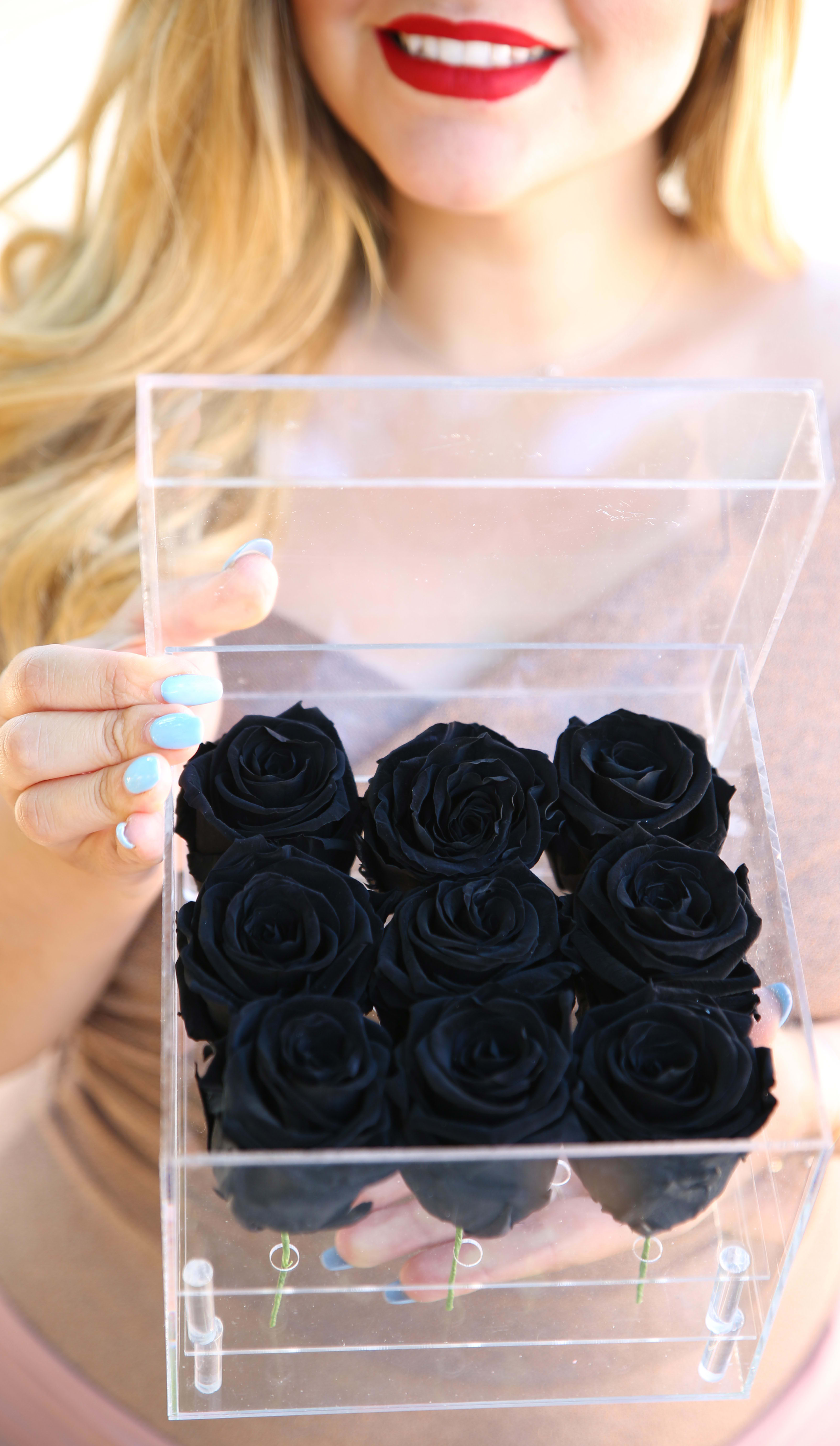 Small Clear Case - 9 All Year Roses in Black - Meet our everlasting roses! These are REAL roses that can last for up to a year! This case is composed of 9 Midnight Black Everlasting Roses. While supplies last, color subject to change based on availability.   About: Our everlasting roses, are imported directly from Ecuador where they are treated with a proprietary solution and color pigmentation process that transforms them into long lasting roses that maintain their freshness and biological structure. The roses are treated using a non-toxic and non-allergenic wax formula that is similiar to silica. The outcome is that our roses continue to look and feel like real roses - because they are real - with the difference being that they will maintain their integrity and color for up to a year.  Maintenance: The only maintenance they require is a light dusting from time to time. Do NOT water the roses. Do NOT remove the roses from their container. Do NOT place anything onto the roses as they can crush and damage them. Avoid direct exposure to sunlight. Keep the arrangement in a room temperature environment. Please note, the lid is meant to stay on the side or bottom of the box. Positioning dark colored roses next to light color roses may result in the darker rose color bleeding onto the light roses. 