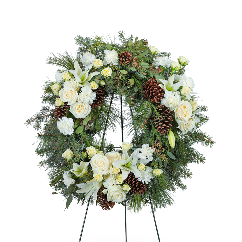 FCS-166 - Our Unforgettable Standing Wreath is a beautiful memorial arrangement featuring roses, carnations, lilies, evergreen, and premium foliage with pinecone accents. The combination of white blooms and lush evergreen foliage creates a serene and elegant tribute. This heartfelt standing wreath honors your loved one with a timeless and peaceful presence.