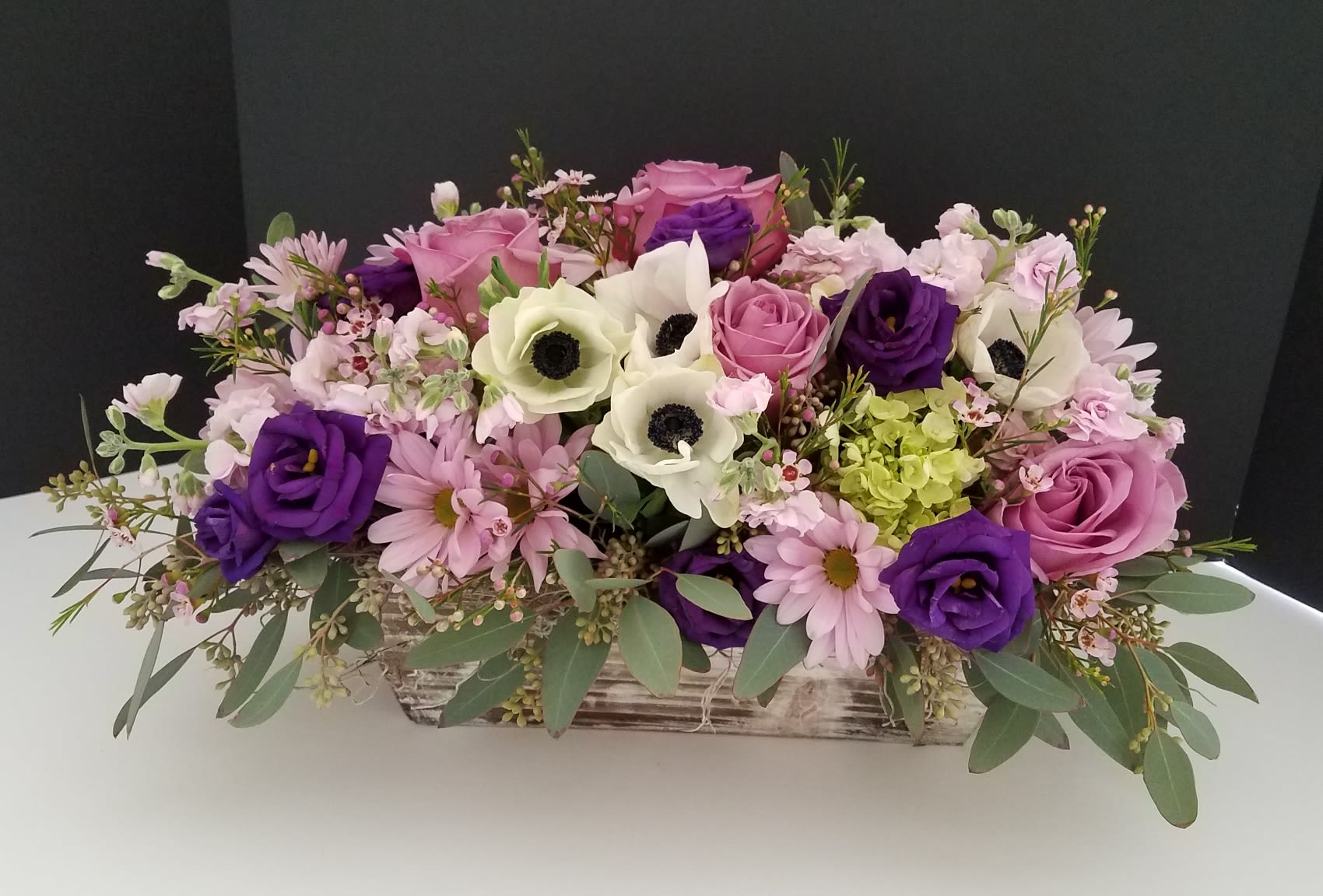 Victoria's Garden - This elegant wooden box is filled with a romantic assortment of flowers including anemone, lisianthus, daisies, stock flower and lavender roses and finished with seeded eucalyptus and moss.