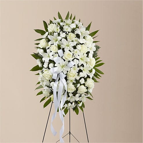 EXQUISITE TRIBUTE STANDING SPRAY-WHITE RIBBON - The Exquisite Tribute Standing Spray is an elegant display of sweet serenity. White roses, Asiatic lilies, chrysanthemums and mini carnations are artfully arranged amongst emerald palm fronds and lush greens. Accented by white satin ribbon and standing on a wire easel, this standing spray is an outstanding way to honor the life of your loved one. Please Note: The bouquet pictured reflects our original design for this product. While we always try to follow the color palette, we may replace stems to deliver the freshest bouquet possible.