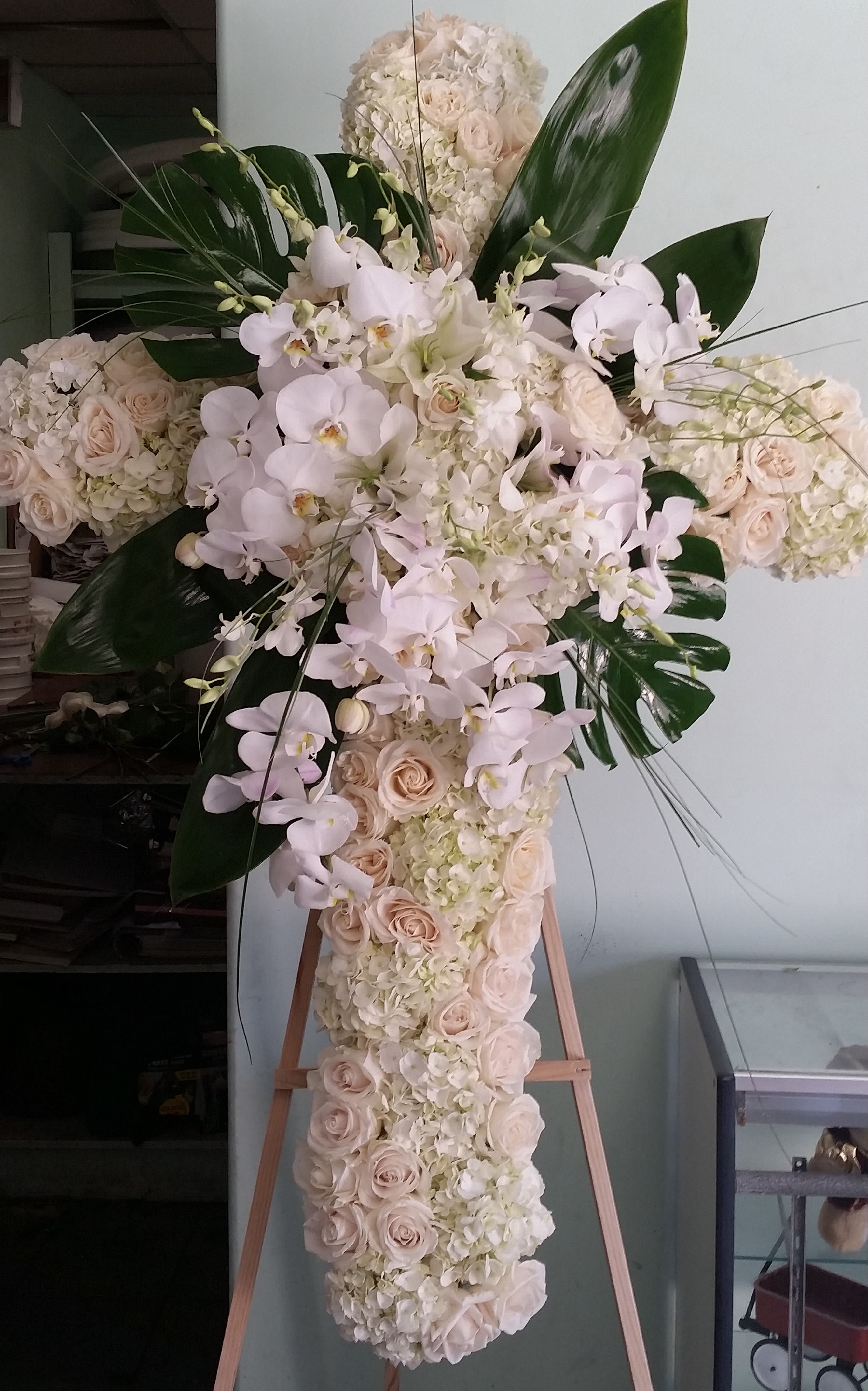Timeless elegance Timeless elegance - Funeral cross with roses, hydrangeas, dendrobium orchids, and phalaenopsis orchids.