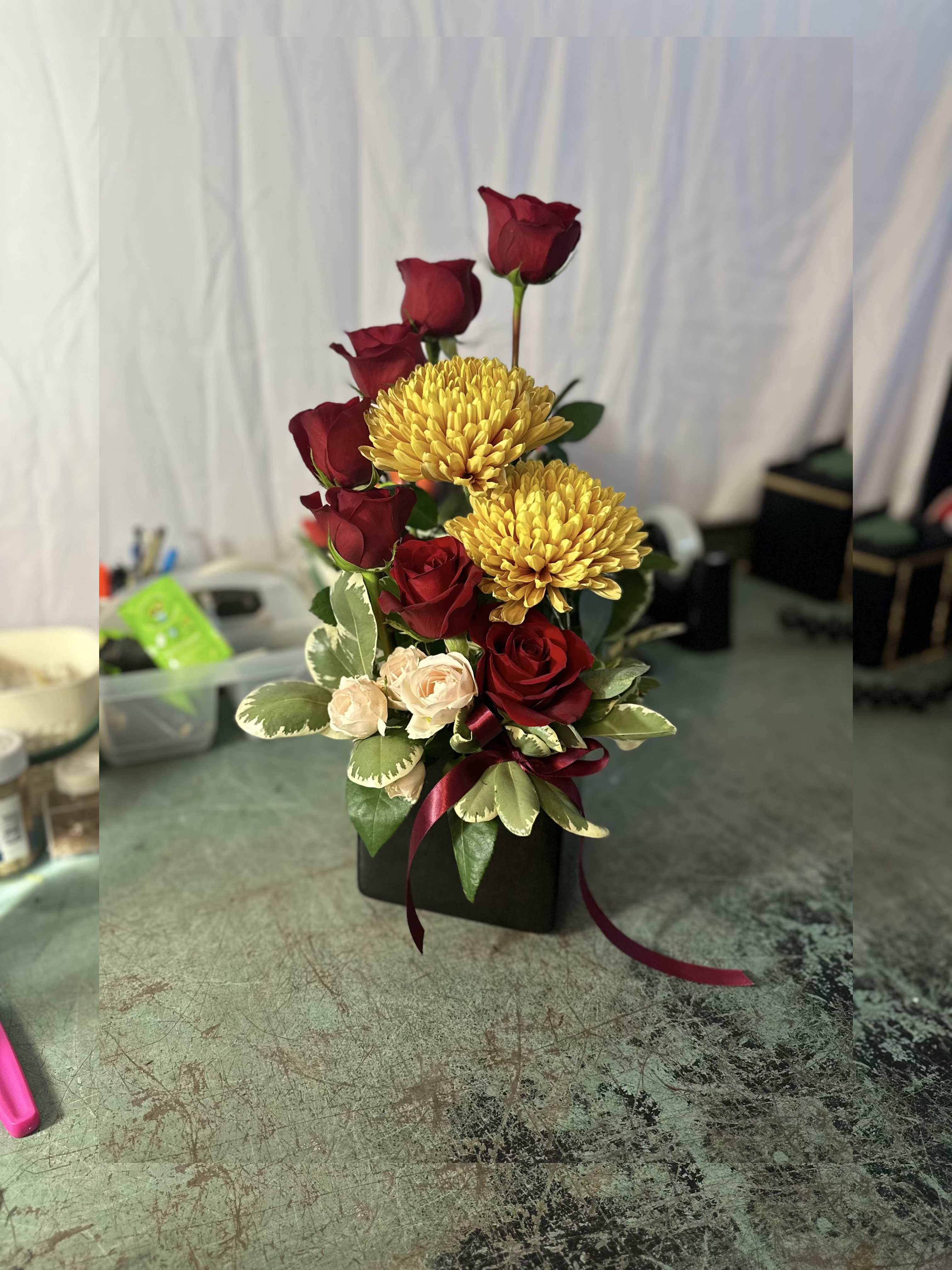 Sun Burst Bouquet - Elegant beauty! This vibrant yellow, gold and red bouquet is a perfect choice for any occasion. A mix of yellow, pink and red flowers including roses, spray roses and chrysanthemums is delivered in a cube vase with ribbon bow.    SUBSTITUTION POLICY If the exact ﬂowers or container you have selected are not available we will create a beautiful bouquet with the freshest available ﬂowers. We will only substitute items of equal or higher value.