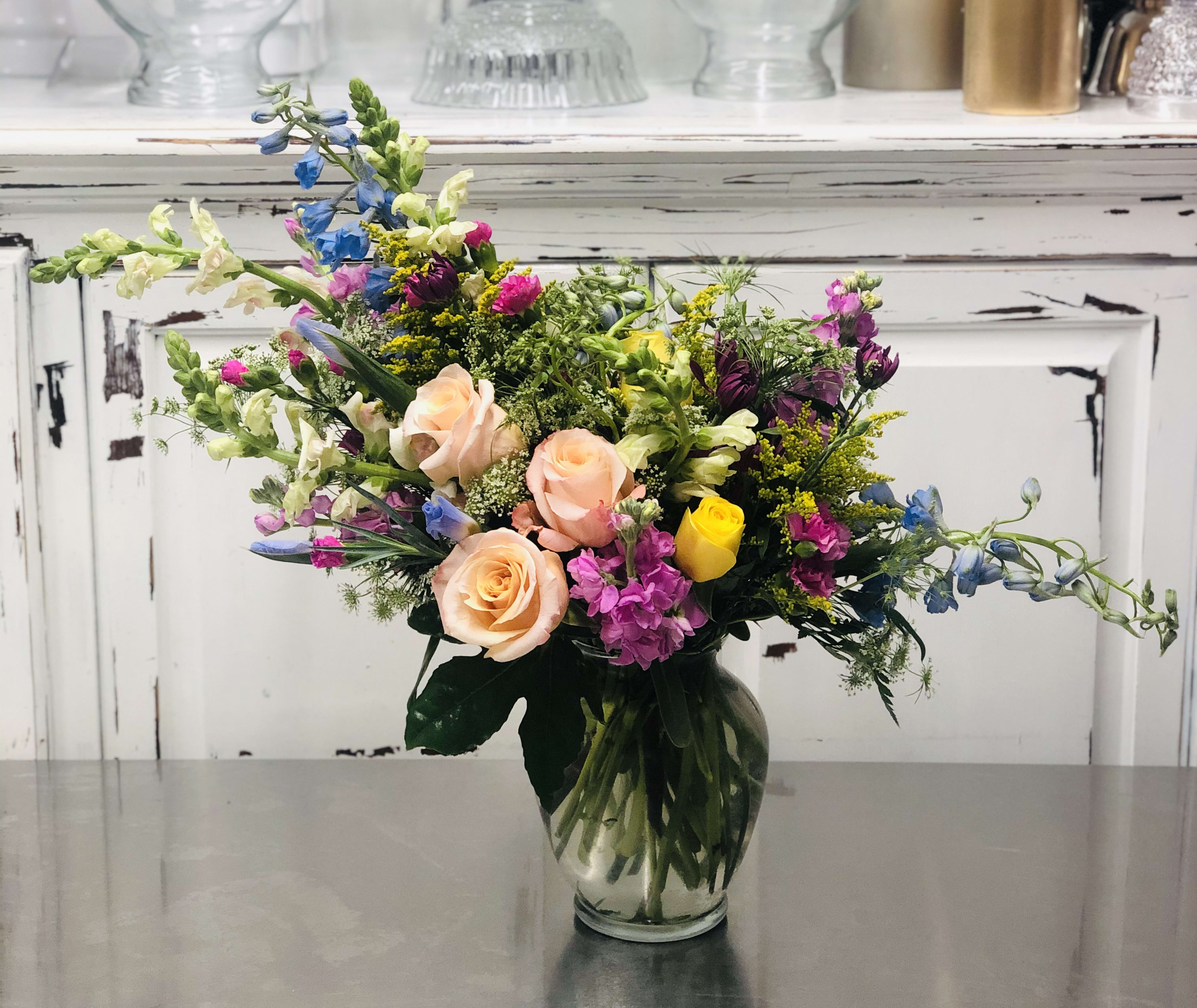 Cascade of Color - This vibrant vase full of cheerful yet delicate Roses, and seasonal blooms cascade over a glass vase in an elegant, asymmetrical line. A great gift for any happy occasion.  * Please note * Florist reserves the right to make modifications to the design based on seasonality and accessibility of blooms and vases.  Any modifications made will honor the color palette, intent, and feeling of the pictured design.  Kindly contact us directly with any specifications or concerns