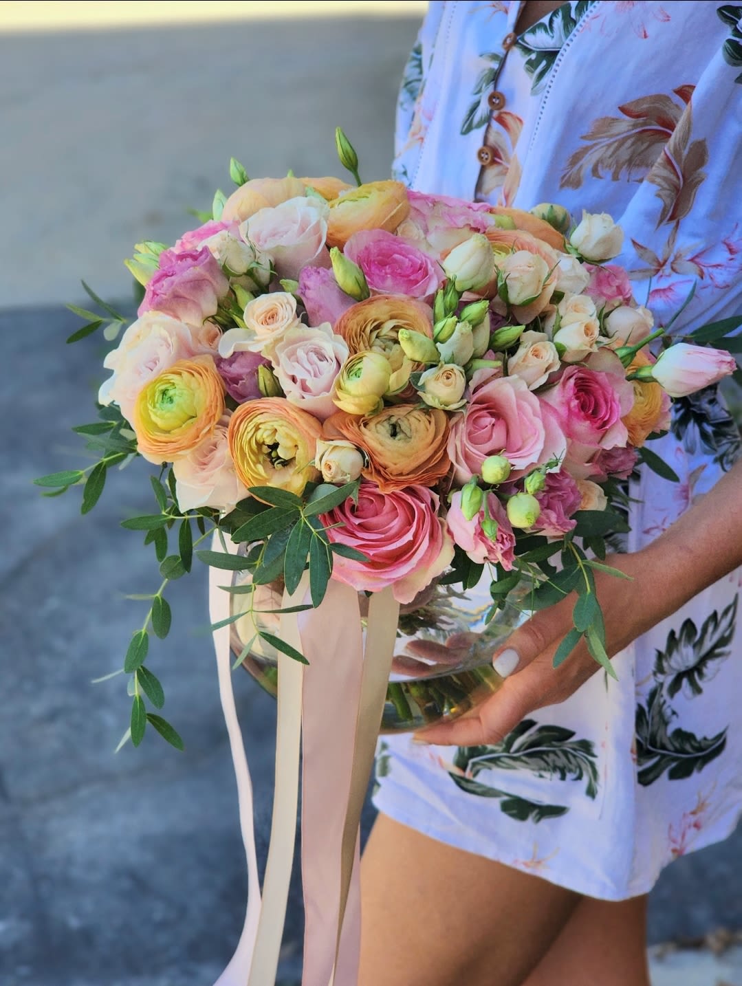 Peach Blush Bouquet  -  A clear vase arrangement featuring peach Ranunculus, pink roses , and mix flowers. Enhanced with a mix of lush greens and fragrant eucalyptus, this elegant floral display is perfect for any occasion. Fresh, stunning, and stylishly simple.