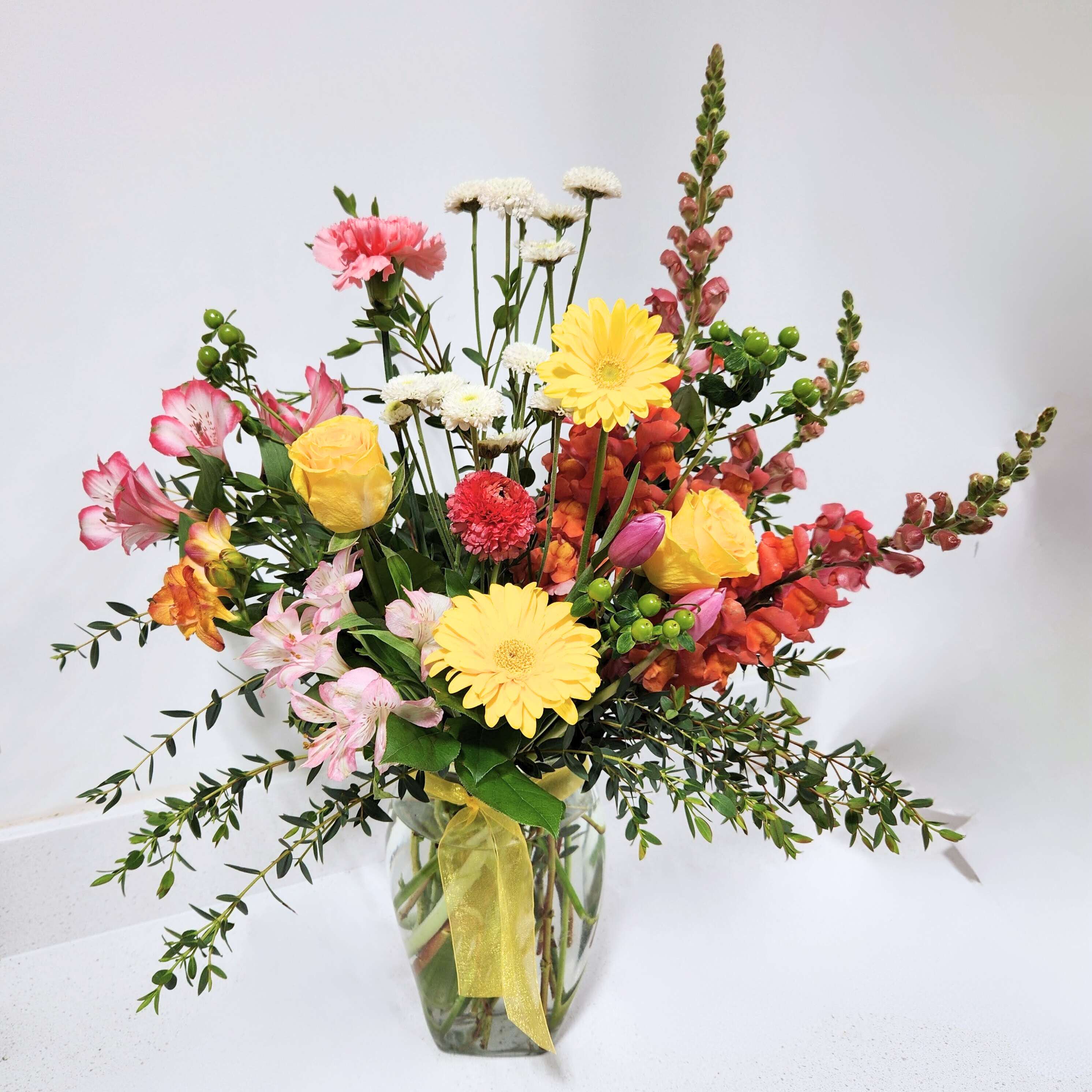 Sunset Beauty - A masterful creation by our esteemed Designer, Adalee, this Sunset flower arrangement is a vibrant homage to the awe-inspiring beauty of any season. Bursting with an exuberant palette of yellows, pinks, whites, and captivating gradient of orange and red, it encapsulates the essence of a vibrant sunset.  Whether you're looking to add a pop of color to your home, seeking the perfect gift to lighten up someone's day, or simply want to celebrate the beauty of nature, this large flower arrangement is an impeccable choice. Experience the magic of any season and beyond with this exquisite piece, and let its radiant beauty bring a smile to your face every day.