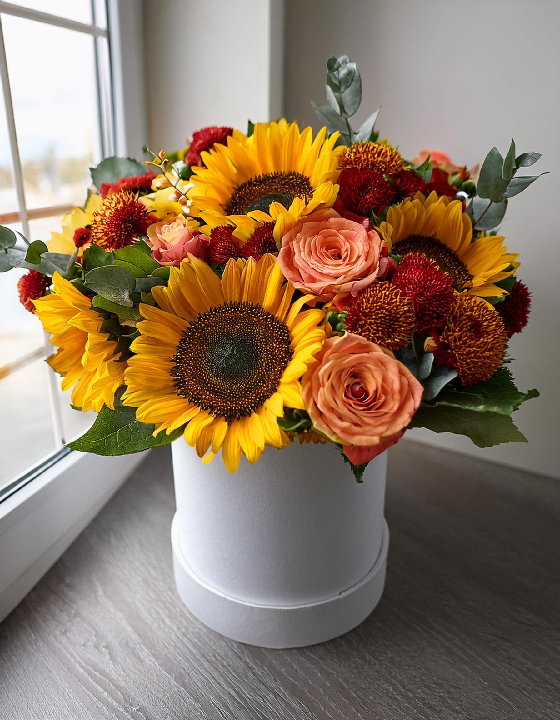 Sunlit Autumn  - Our white hatbox arrangement features the rich hues of fall orange roses, sunflowers, and a mix of autumn flowers. It’s a beautiful way to welcome the season. Purchase now and let your home glow with autumn's beauty.