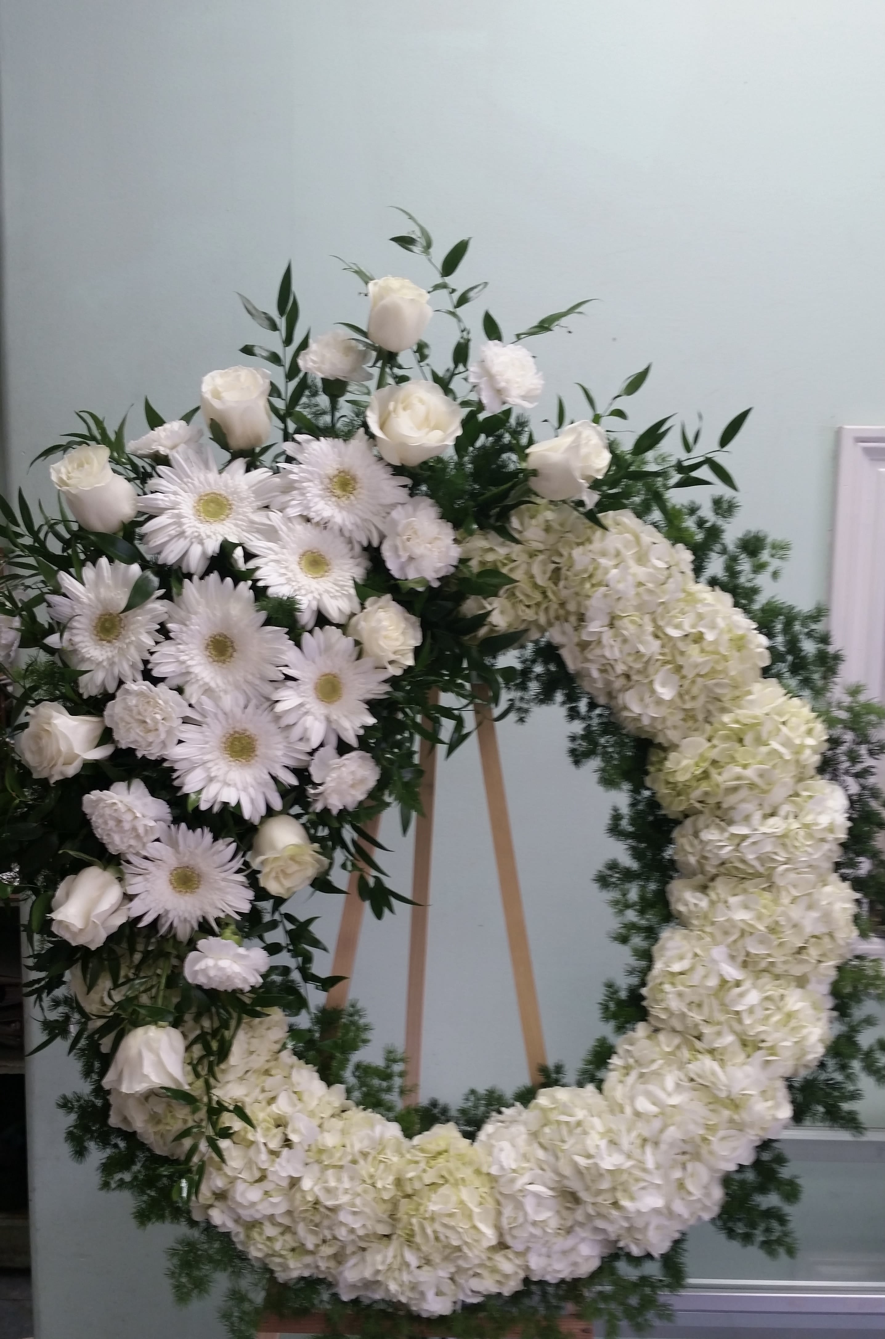 Divine Light  - Open wreath with white gerbera daisies, carnations, roses, and hydrangeas.
