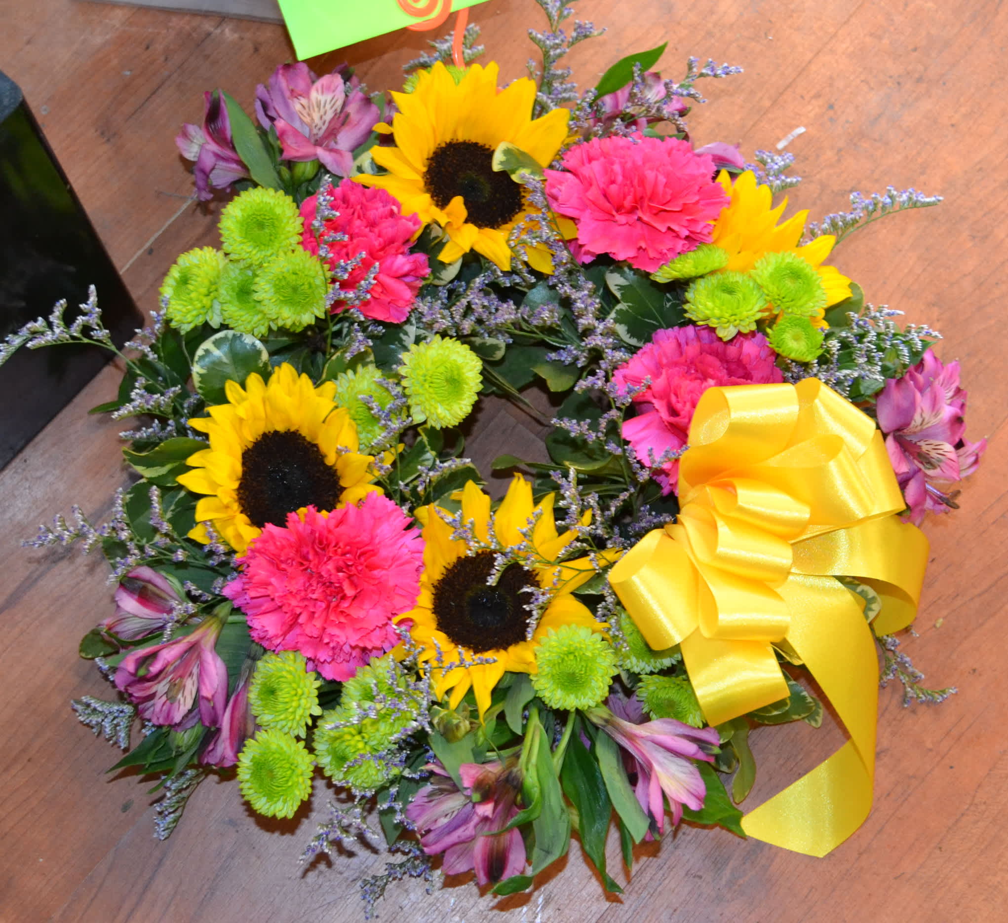 Celebration of Life - This colorful wreath with Sunflowers, Carnations, Green button poms and more is sure to convey your deepest sympathies.