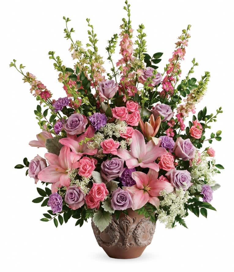 Teleflora's Soft Blush Bouquet - Like a whisper from heaven, the soft pinks and lavenders in this feminine arrangement bring peace and hope in a time of loss. Presented in a large antiqued pot, it's a loving tribute all will appreciate. This soft pink arrangement features lavender roses, pink spray roses, pink asiatic lilies, lavender carnations, pink larkspur, queen anne's lace, huckleberry, dusty miller, and leatherleaf fern. Delivered in Teleflora's Classical Garlands pot. Orientation: One-Sided  SUBSTITUTION POLICY – Always deliver the freshest flowers! Please note the bouquet pictured reflects our original design.  If the exact flowers or container in this arrangement are not available, our local florists will create a beautiful bouquet with the freshest available flowers.
