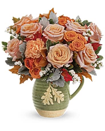 Teleflora's Rosy Autumn Bouquet Teleflora's Rosy Autumn Bouquet - Teleflora's Rosy Autumn Bouquet is presented in a food- safe, glazed stoneware pitcher filled with fall flowers such as roses, carnations, and sinuata statice. This fall arrangement is sure to bring a rosy outlook to your loved one's life. Peach roses, orange spray roses, orange carnations and white sinuata statice are arranged with dusty miller and variegated pittosporum. Delivered in Teleflora's Charming Acorn Pitcher.