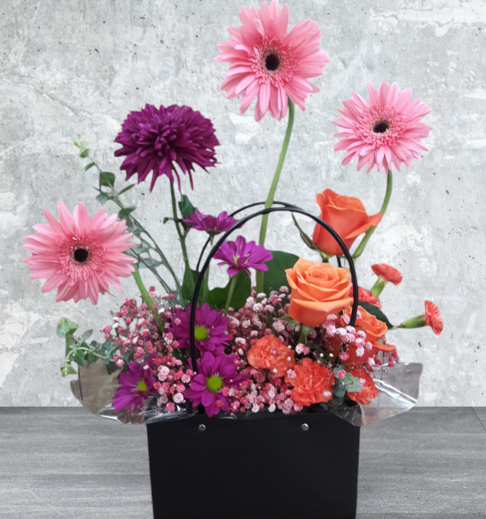 Posh Petals Purse Posh Petals Purse - Elevate your floral experience with the "Posh Petals Purse" – a stunning arrangement that’s as stylish as it is vibrant. This eye-catching design features a delightful mix of gerbera daisies*, roses, cremon, carnations, and classic daisies, all in enchanting shades of pink, purple, and orange. Arranged in a chic purse-shaped vase, it’s the perfect fusion of elegance and whimsy. Whether you’re celebrating a special occasion or simply brightening up your space, the "Posh Petals Purse" is sure to make a fashionable statement and add a touch of floral glamour to any setting. * Gerbera Daisies may not always be available. We will substitute accordingly with a flower of equal or greater value.