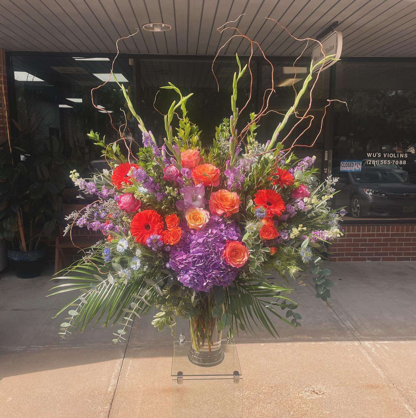 Exploding passion Exploding passion - An absolutely beautiful mixture of bright and colorful roses, bold purple hydrangeas, and other complementary flowers with mixed greens and an accent of curly willow. This arrangement is gigantic, beautiful and bold.