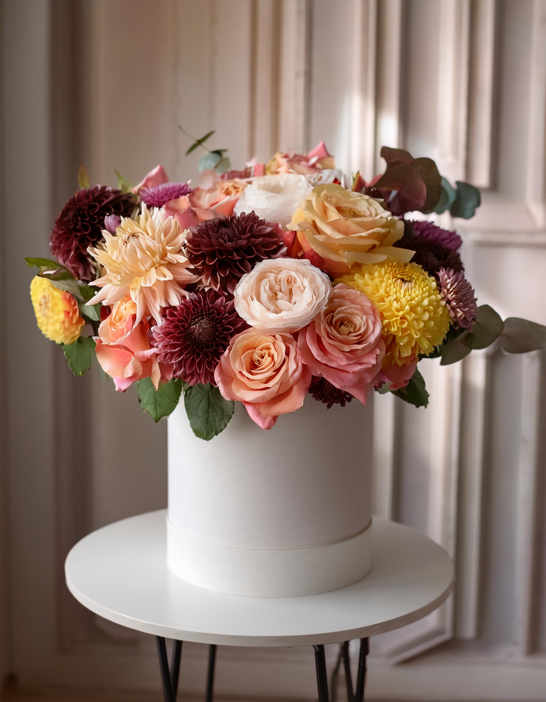 Splash of Colors Splash of Colors - Vibrant floral arrangement, beautifully displayed in a white hatbox. This stunning mix of flowers in captivating shades of pink, orange, yellow, and purple. Eye-catching bouquet that exudes elegance and joy. Perfect for adding a splash of color to any occasion