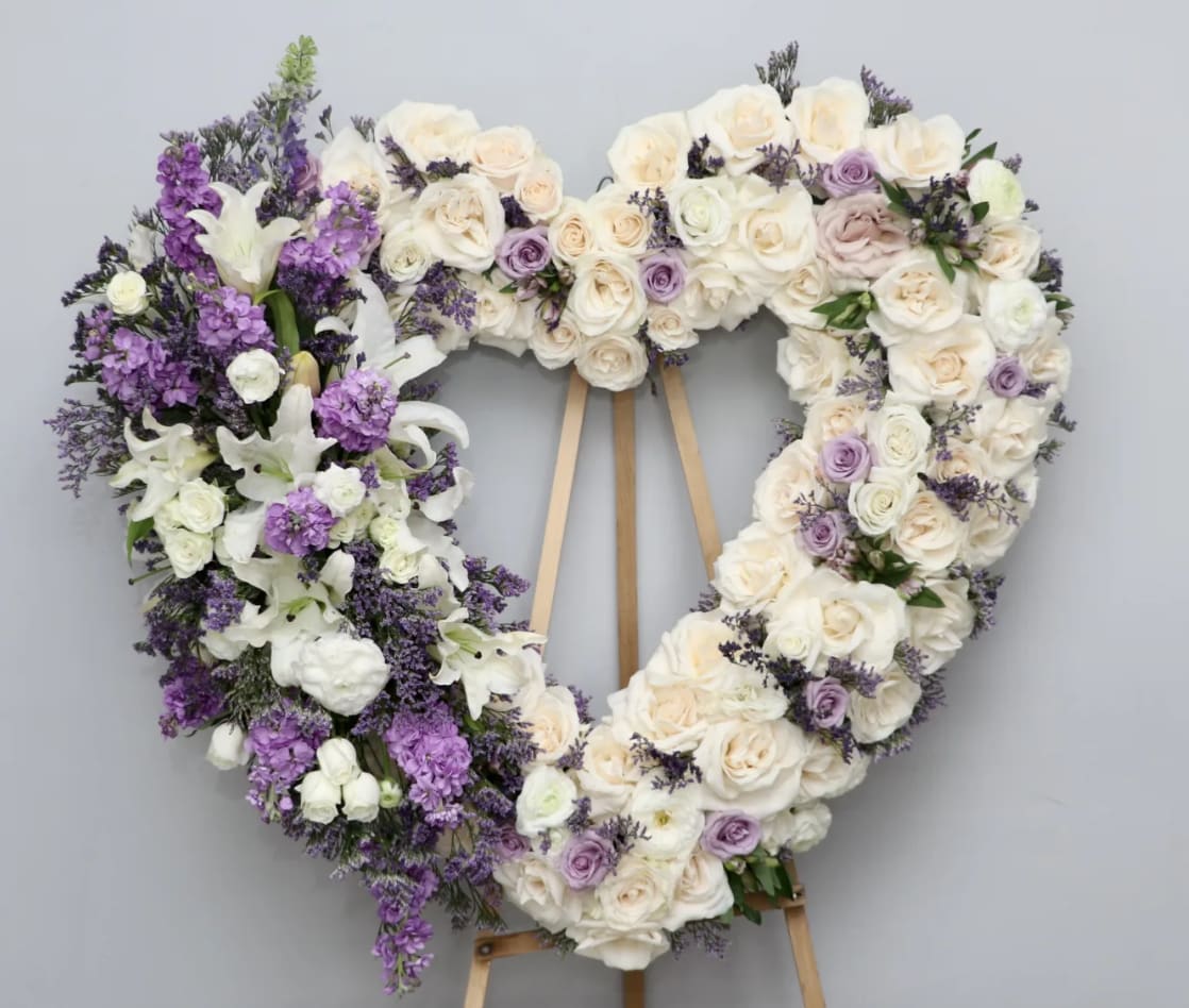 Lavender and White Heart  - This heart includes white roses, lilies, and lavender roses.     We include easel, printed banner and delivery (some fees may apply). An additional banner can be added for $15    Standard size is 30'', deluxe is 36'', and premium is 42''.