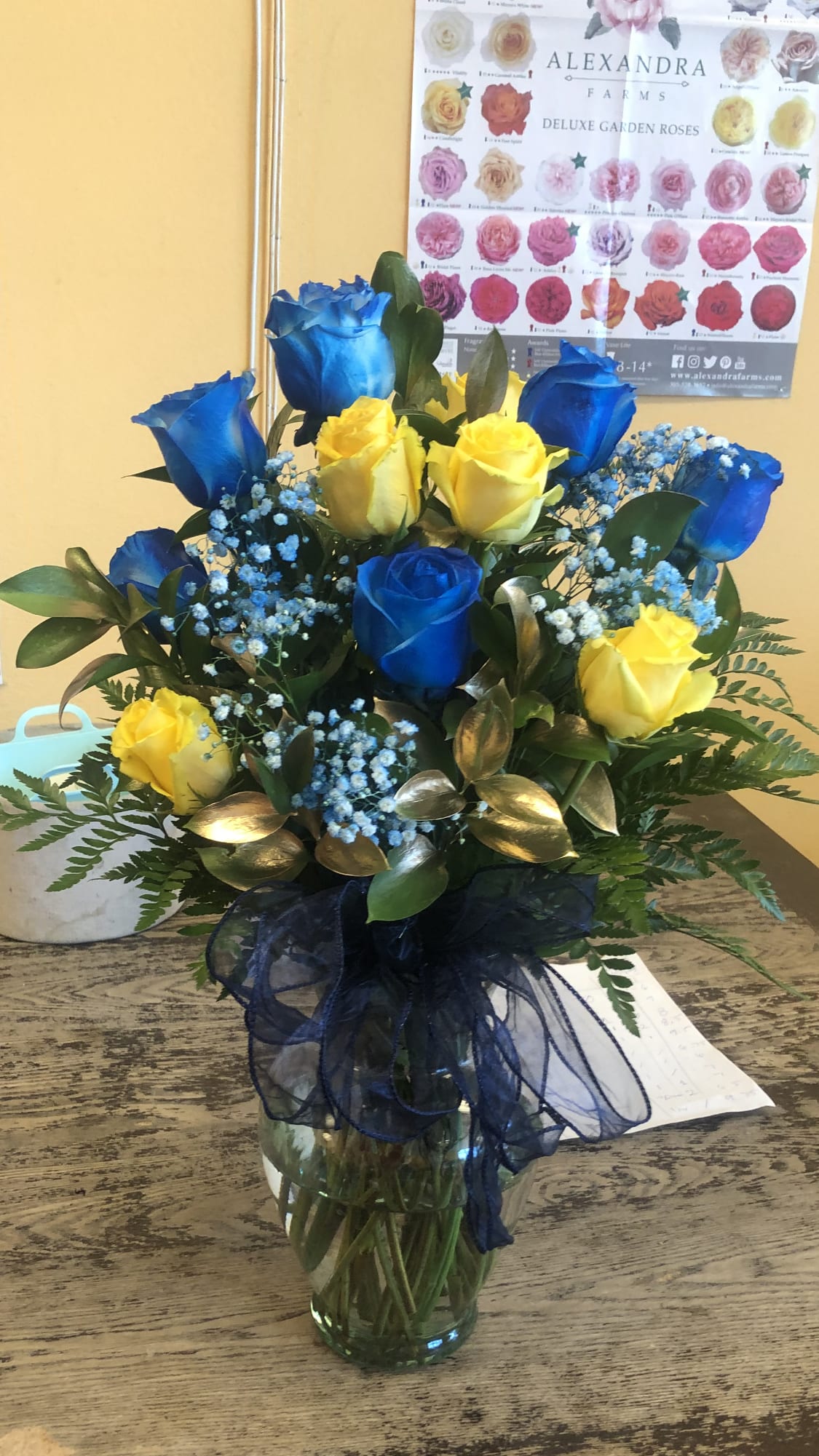 YELLOW AND BLUE ROSES MODERN STYLE YELLOW AND BLUE ROSES MODERN STYLE - 6 YELLOW ROSES AND 6 BLUE ROSES IN A VASE WITH GOLD RUSCUS AND BLUE BABY BREATH VERY IMPORTANT (THE BLUE ROSES AND THE BABY BREATH ARE SPRAY PAINTED TO GIVE IT THE BLUE COLOR) STANDARD PRICE INCLUDES 12 ROSES DELUXE PRICE INCLUDES 18 ROSES PREMIUM PRICE INCLUDES 24 ROSES