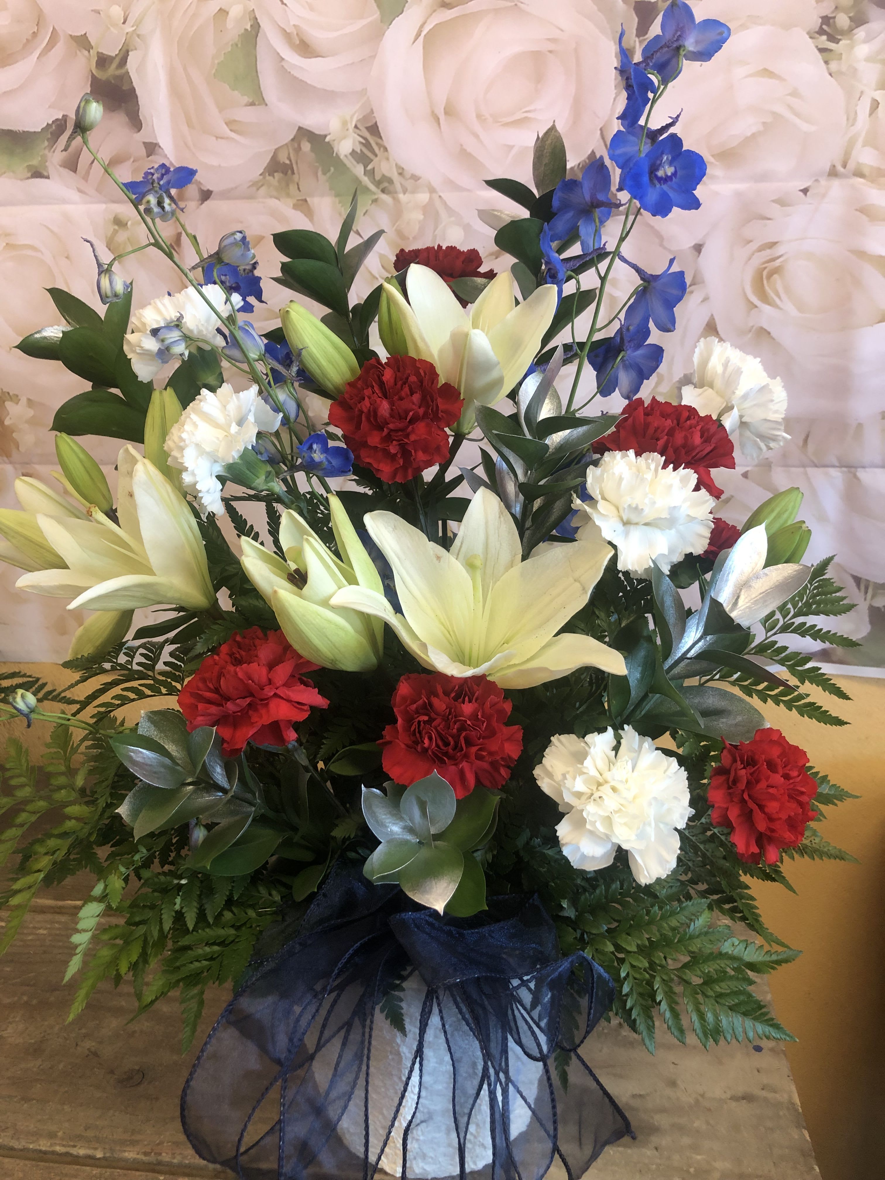 Farewell My Friend Farewell My Friend - RED AND WHITE CARNATIONS, WHITE LILIES AND BLUE DELPHINIUM WITH SILVER RUSCUS INSIDE A PAPER MATCHE CONTAINER. VERY UNIQUE AND ELEGANT ARRANGEMENT. Standard price includes items stated above Deluxe price will include items stated above and 4 red roses and extra lily. Premium price will include items stated above and 8 red roses and extra lily and bigger container.