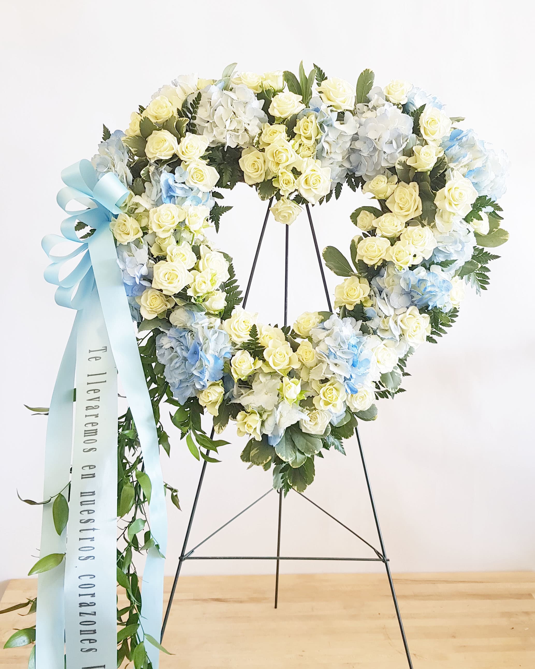 Pure Heart Pure Heart - This beautiful and petite, 16" heart-shaped wreath (standard)of sky blue hydrangea and snow white roses is a touching tribute to your love. This heartfelt arrangement features blue hydrangea, white spray roses, and variegated ivy. Delivered on a wire easel. (banner word print $15)