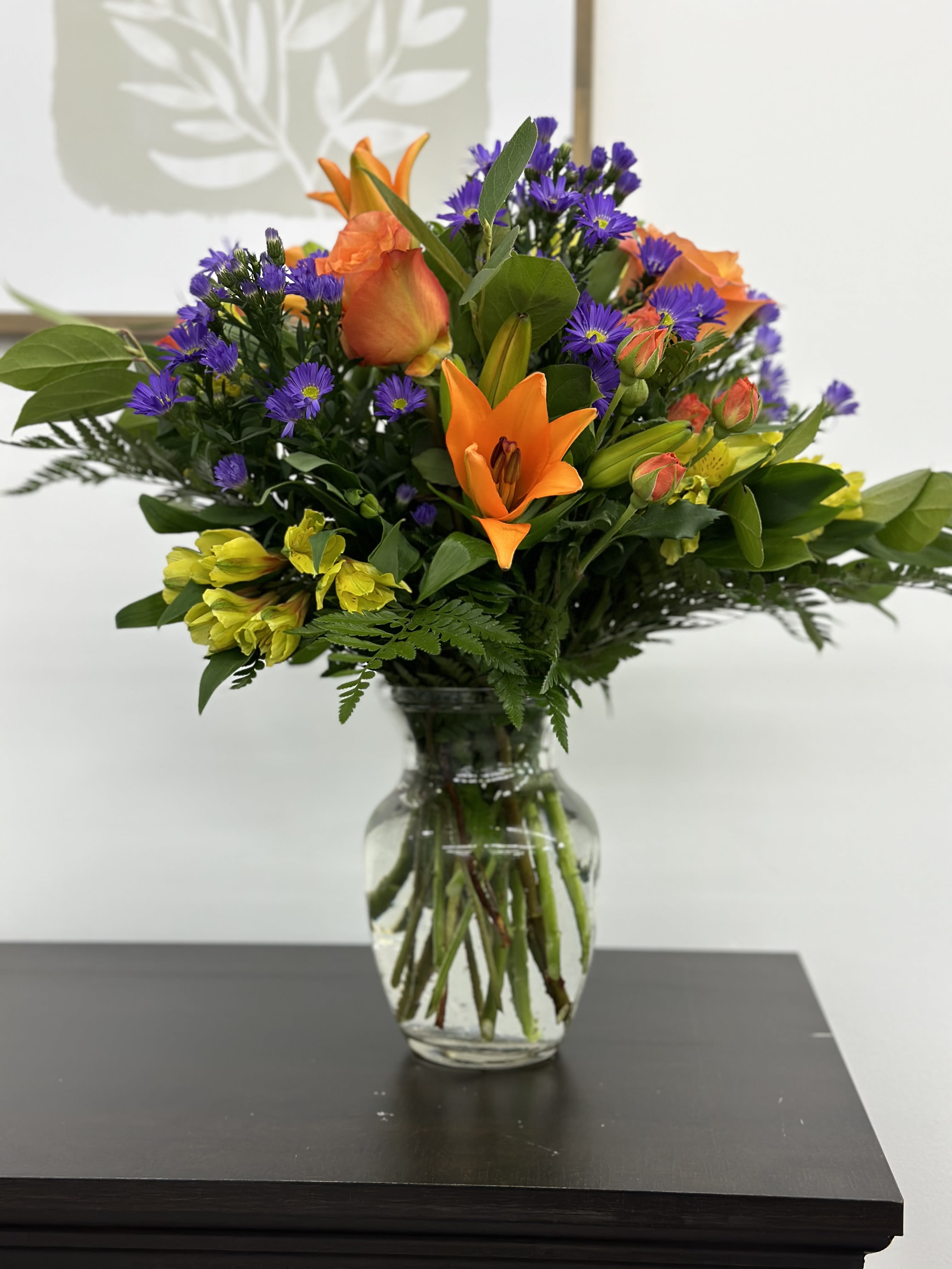 Good Morning Bouquet - This sunny and bright arrangement includes orange roses, orange spray roses, orange asiatic lilies, purple asters, yellow alstroemeria, and assorted greens. Brighten up someone's home with this beautiful arrangement. 