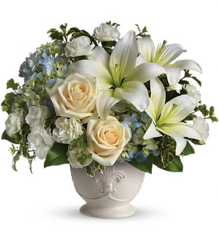 Beautiful Dreams - Soothing and respectful. Calm and compassionate. This beautiful collection of white and light colored blossoms will deliver your loving thoughts perfectly.  Tasteful flowers such as light blue hydrangea, crème roses, white asiatic lilies, miniature carnations and more are delivered in a lovely white French Country Pot. Approximately 13&quot; W x 12&quot; H