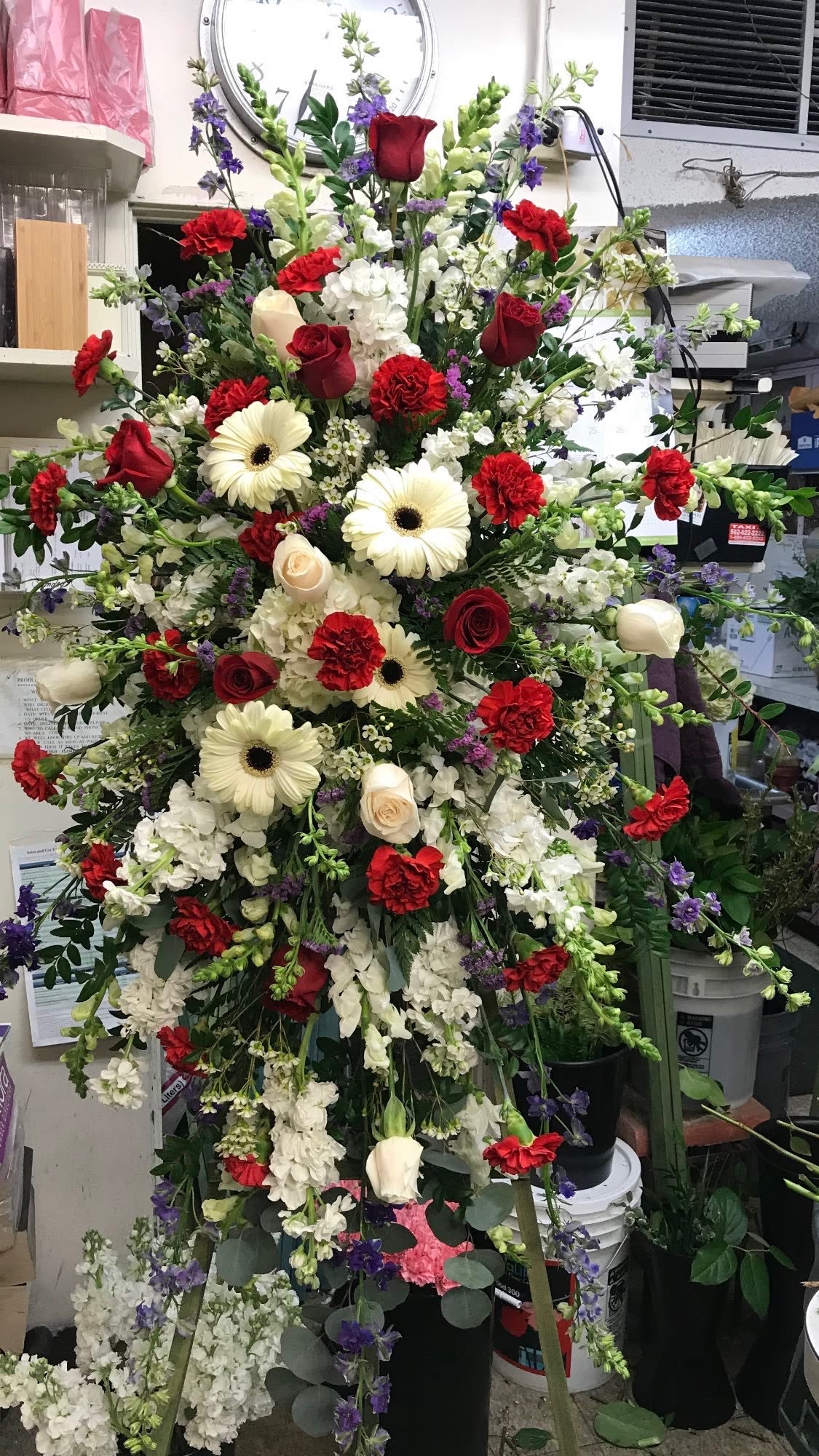 Everlasting Everlasting - Beautiful white gerbera daisies, red carnations, red and white roses, purple and white larkspur, white gladiolus and filler flowers. Large standing spray tribute.