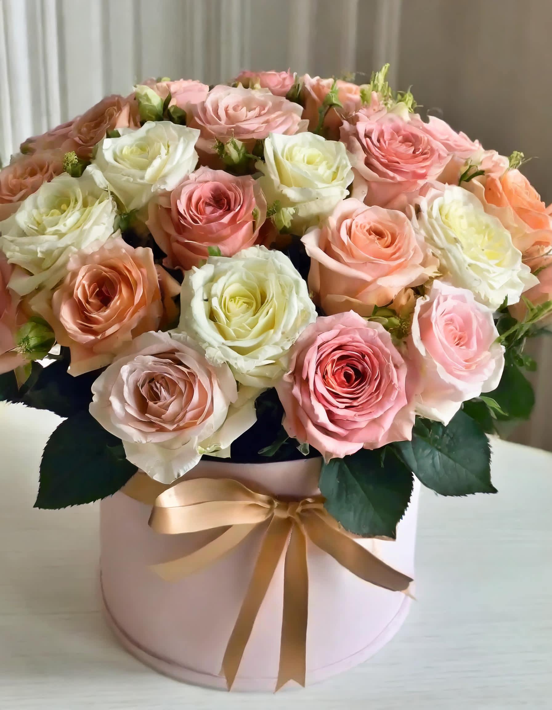 Petal Playful - A hatbox filled with a delicate arrangement of white, cream, and light pink roses exudes elegance and charm. Their soft tones symbolize warmth and affection, expressing sentiments that transcend mere words. When presented in a luxurious hatbox, these roses become not just a gift but a beautiful gesture of love and admiration.  