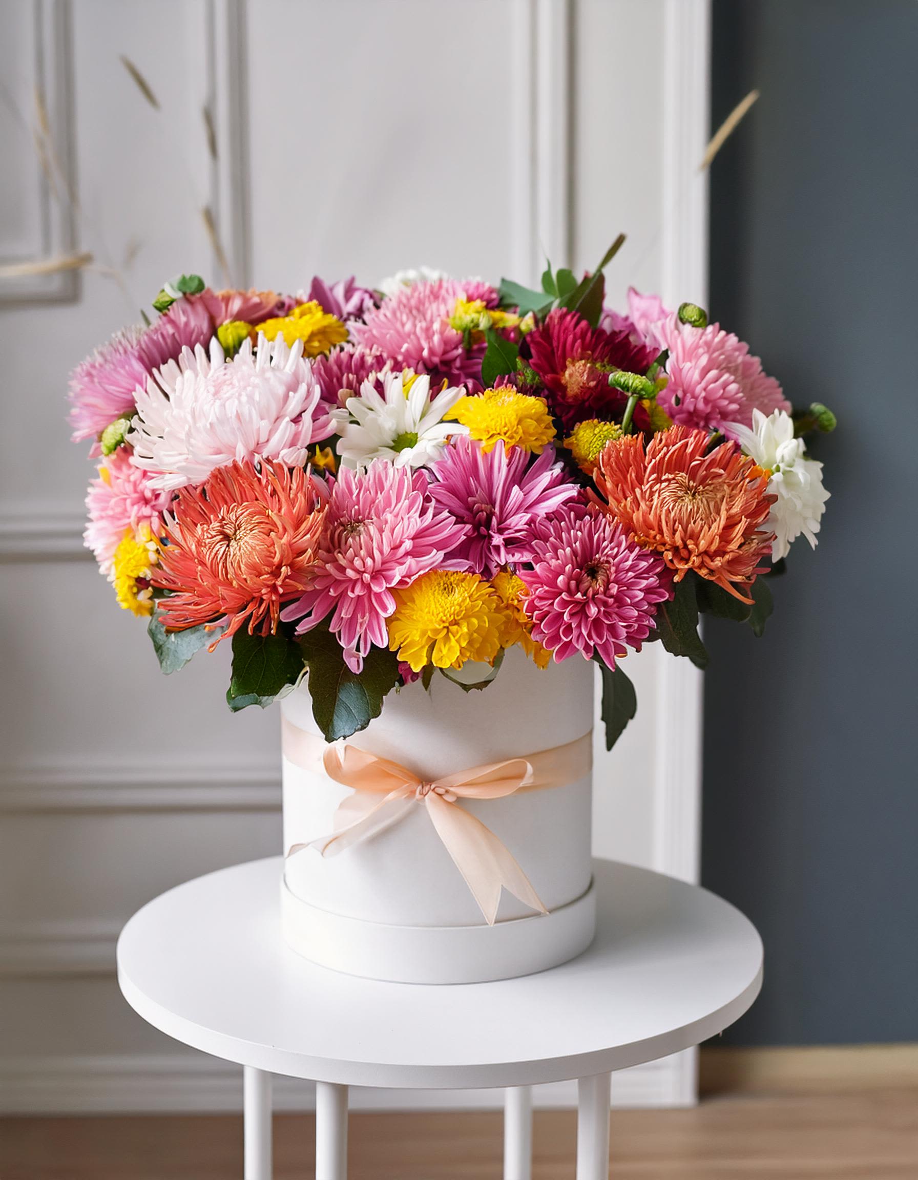 Charming Autumn Charming Autumn - Vibrant floral arrangement, beautifully displayed in a white hatbox. This stunning mix of flowers in captivating shades of pink, orange, yellow, and purple. Eye-catching bouquet that exudes elegance and joy. Perfect for adding a splash of color to any occasion