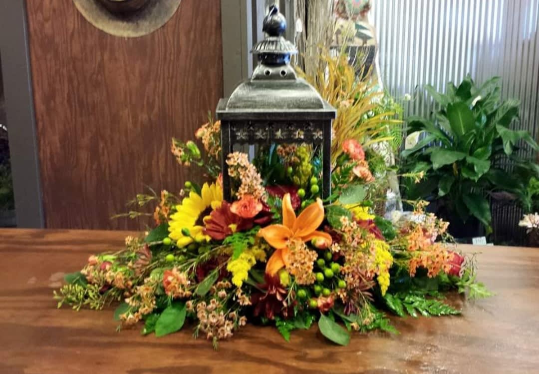 Open lantern bouquet - This arrangement contains an open metal lantern. The flowers in the bouquet are made on the base extending out beyond the lantern in all directions. This can be made to reflect the season we are currently in.  