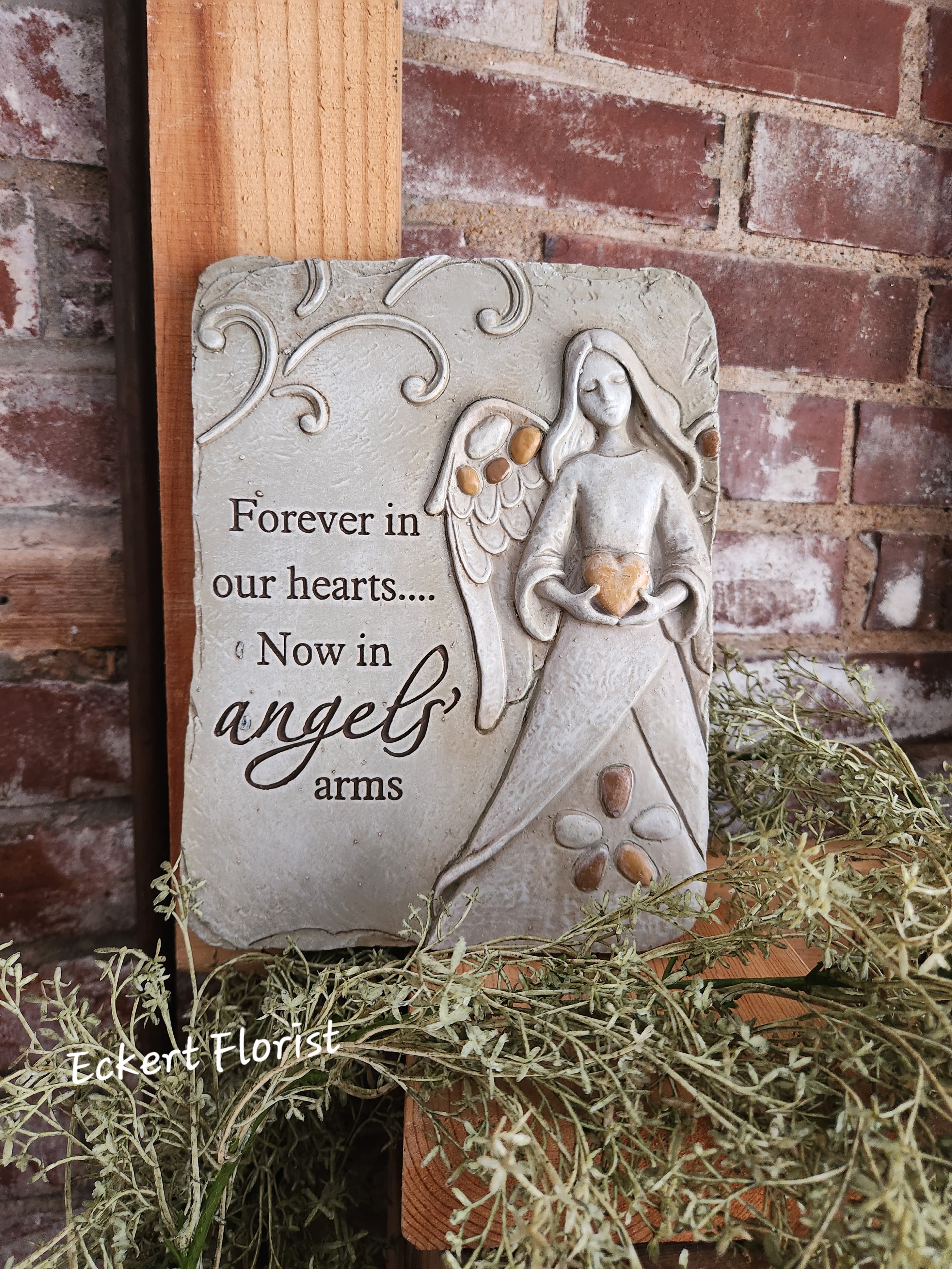 Eckert Florist's &quot;Forever In Our Hearts...&quot; Memorial Stone *Our local delivery only - Resin stone measures approx. 9.5&quot; H x 7.25&quot; W This nice memorial keepsake may be sent to a funeral/memorial service or home. Can be added to a green plant or fresh arrangement. See Deluxe or Premium upgrades. Sentiment: &quot;Forever in our hearts....Now in angles arms&quot; *See Add-on Section for Display Easel *LOCAL DELIVERY ONLY